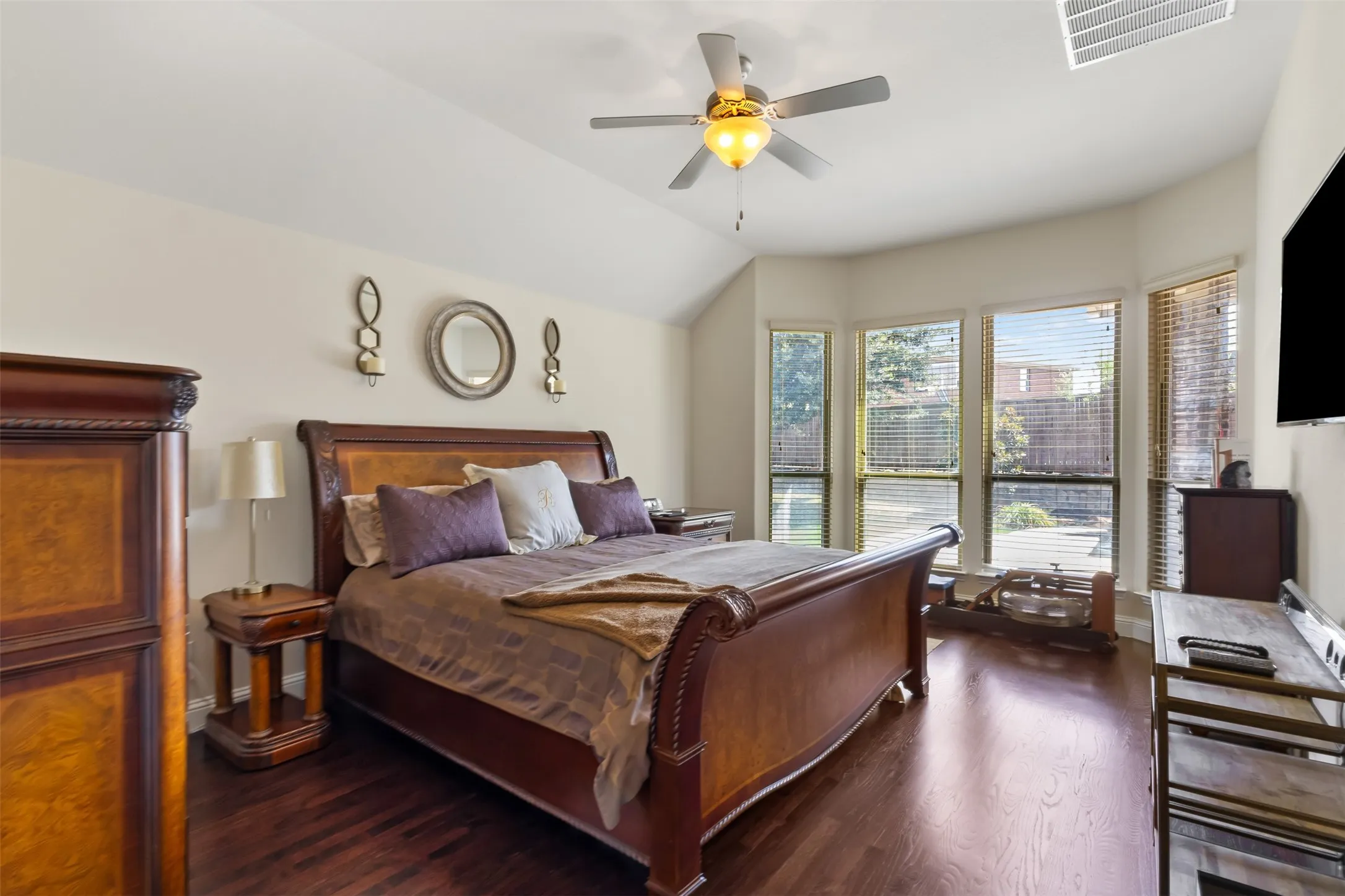 Vaulted ceiling with a ceiling fan, bay window featuring multiple panes, wood-finish flooring, and neutral wall tones
