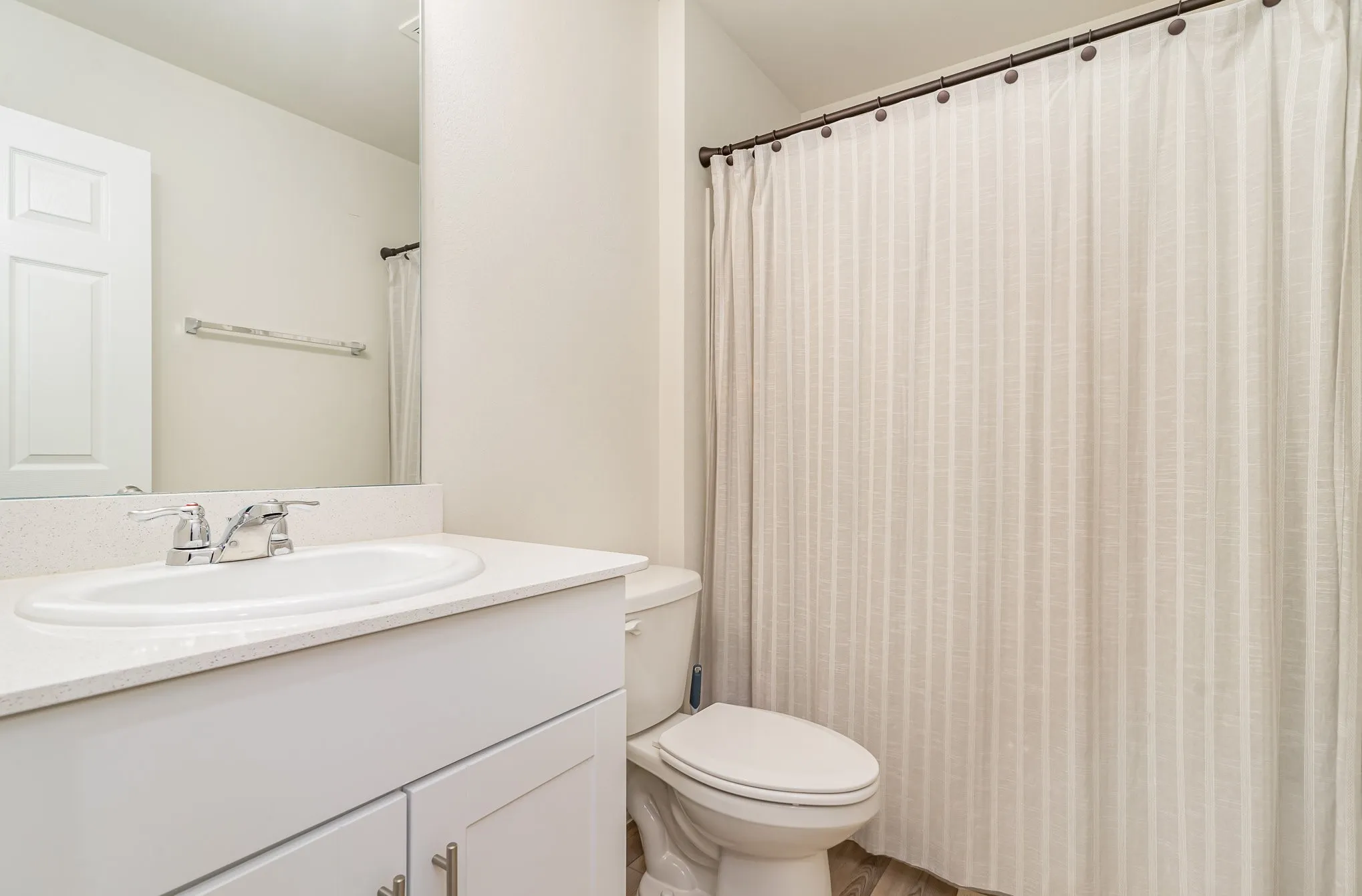 White vanity with integrated sink, chrome faucet, and quartz-finish countertop