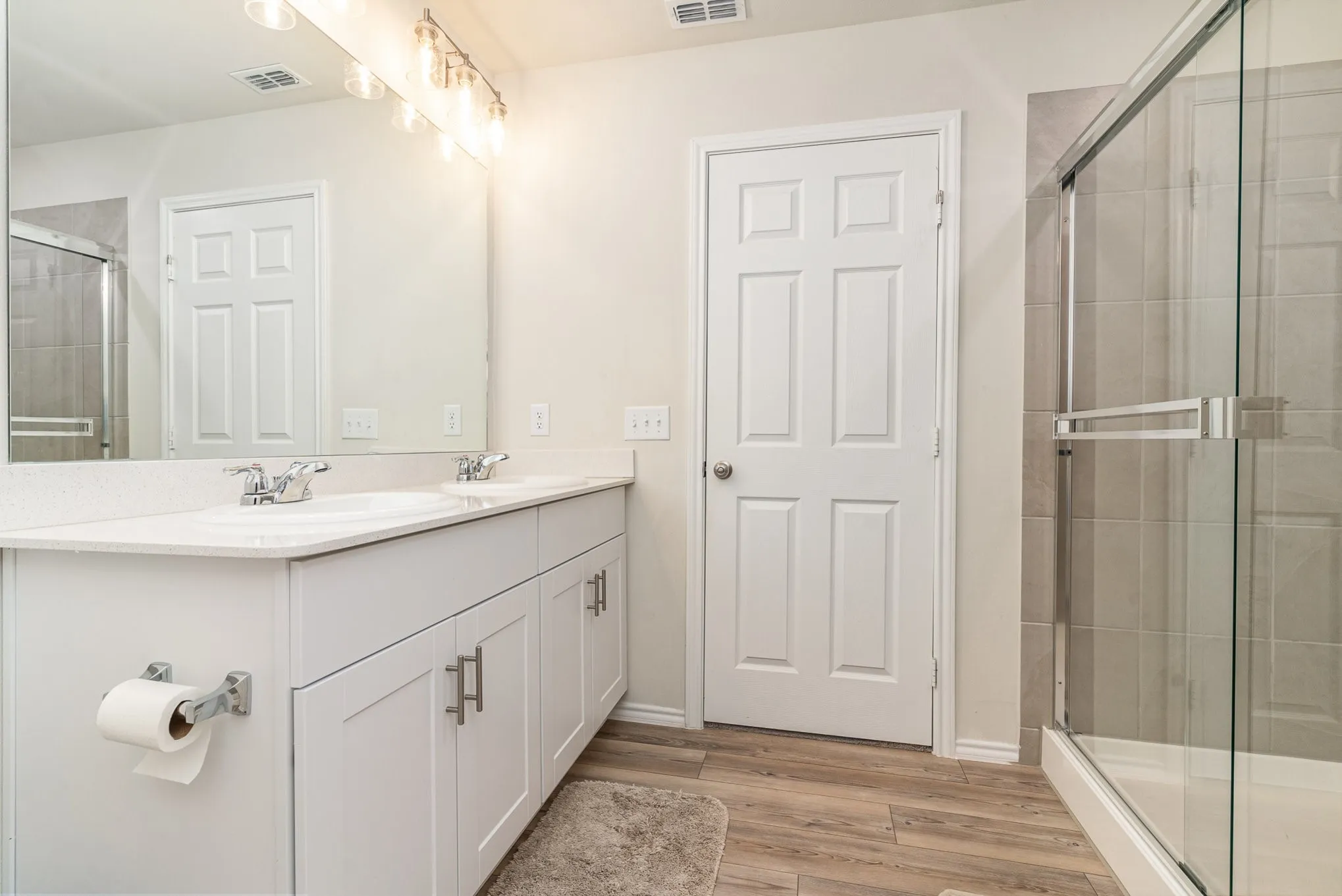 Double vanity with white cabinetry, light-colored countertops, and chrome fixtures