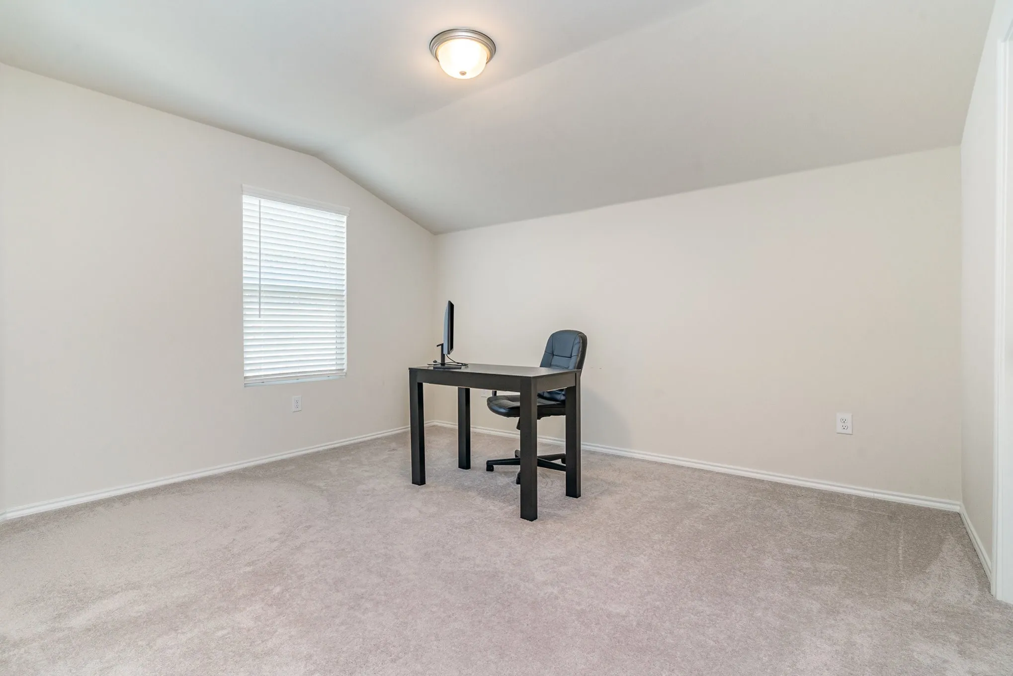 Neutral wall color, window with blinds, vaulted ceiling, flush mount lighting, and carpet flooring
