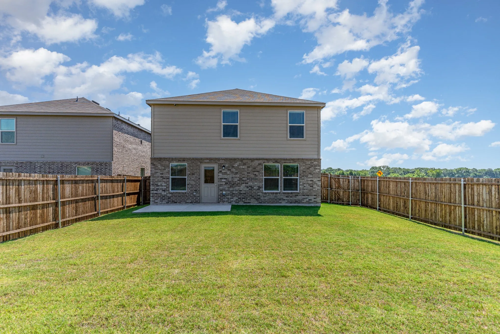 Expansive backyard with a manicured lawn, full wood fencing, and a concrete patio