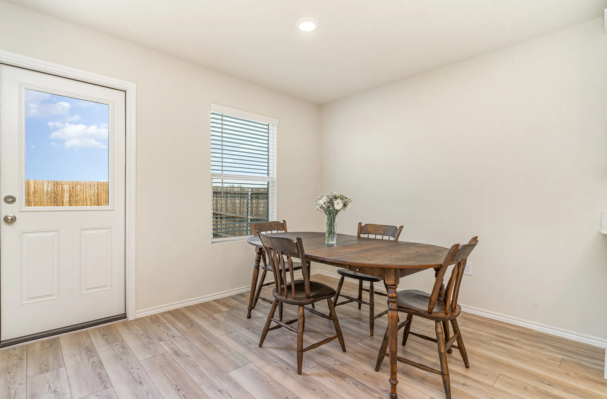 Light wood-finish flooring, white walls, and a white exterior door with a clear glass panel