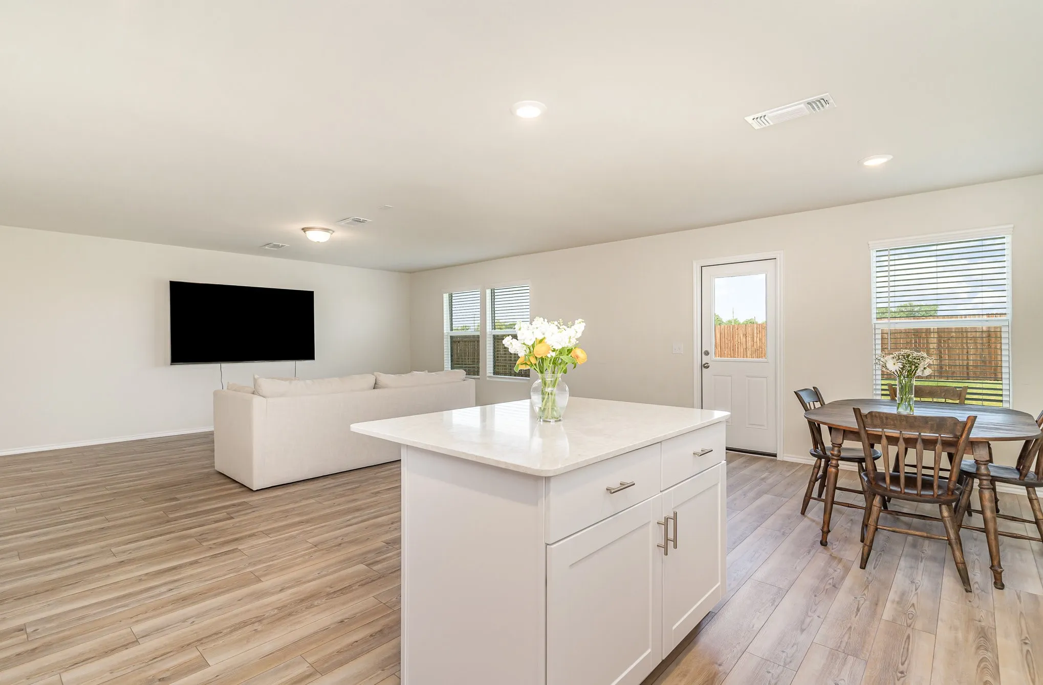 Open-concept living space featuring wood-finish flooring, recessed lighting, and a kitchen island with a light-colored countertop