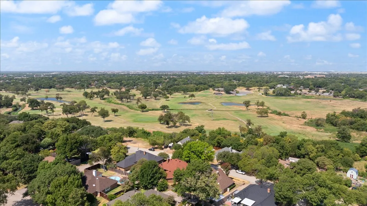 Expansive community featuring mature trees, residential properties, and a golf course with multiple greens and water features