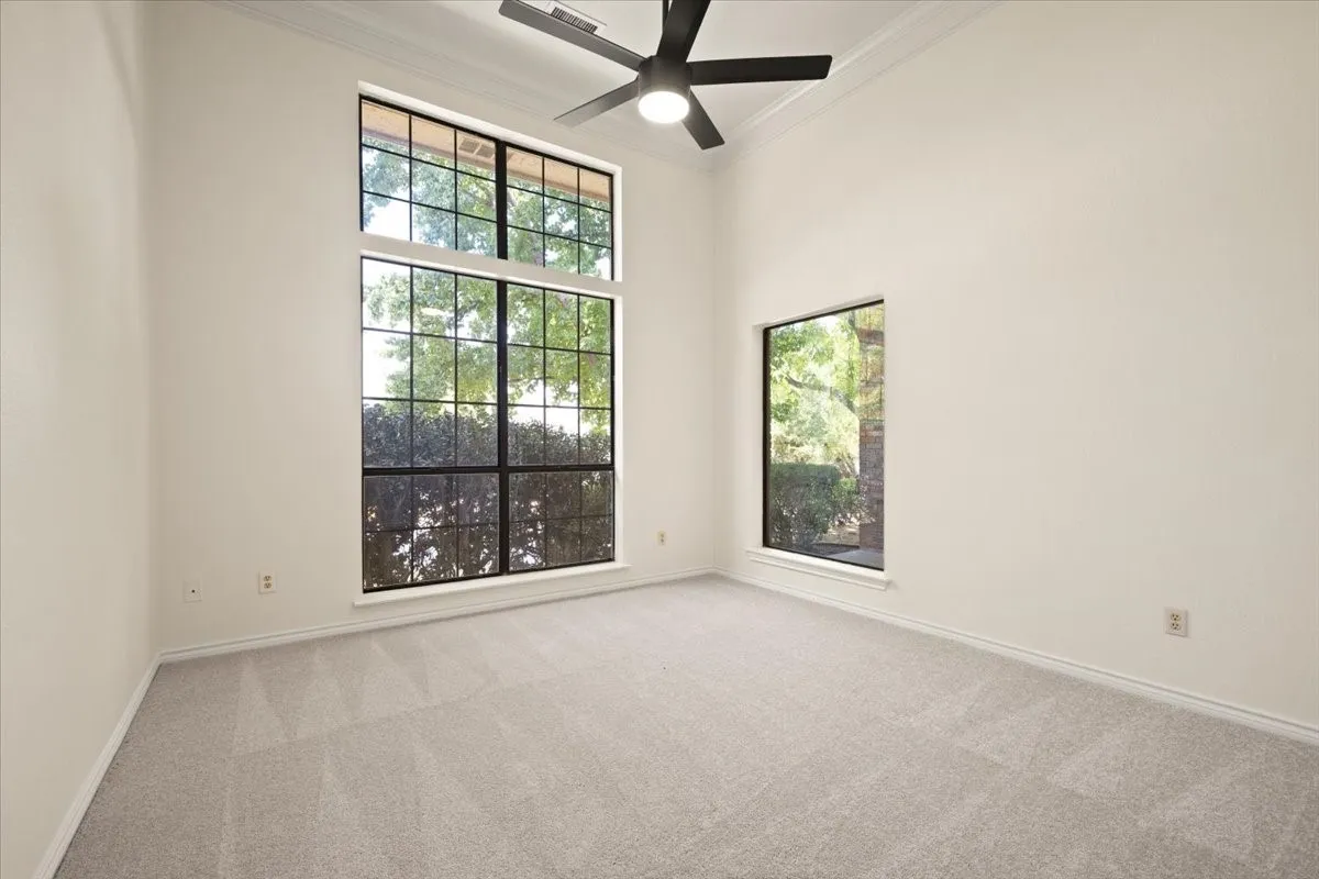 Vaulted ceiling with an attached ceiling fan, large window with grid panes, secondary window, and neutral carpeting
