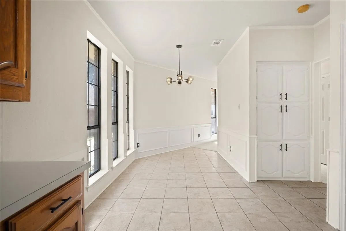 Tile flooring, wainscoting, recessed lighting, built-in cabinetry, and a contemporary chandelier