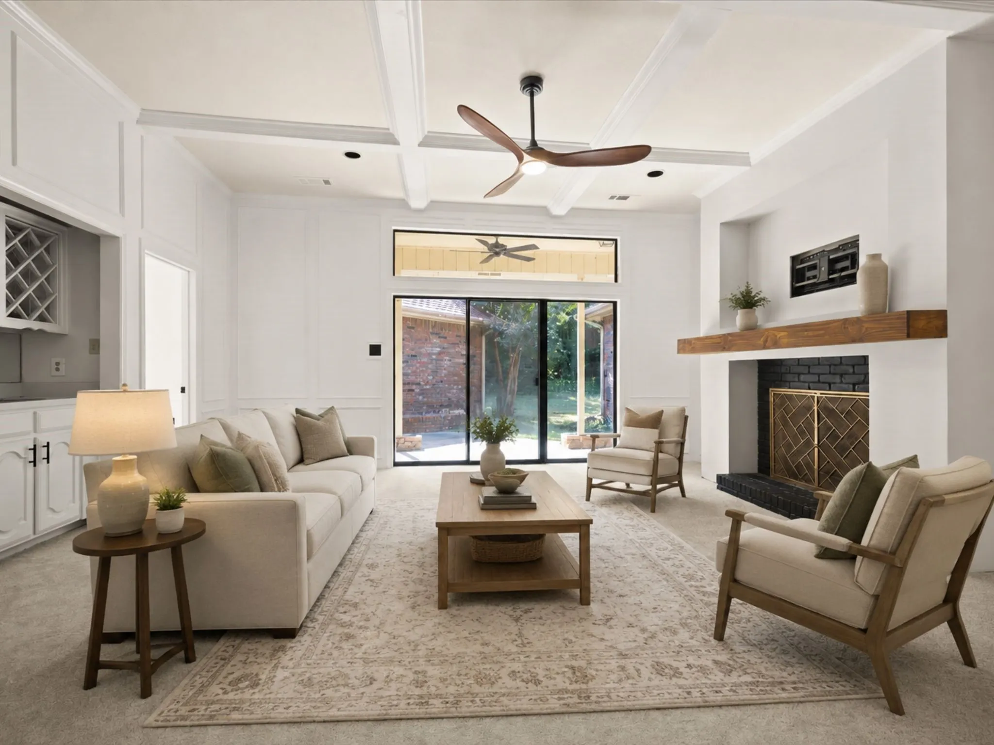 Coffered ceiling with a modern ceiling fan, wood-burning fireplace with a timber mantel, full-height sliding glass door, and built-in cabinetry with a wine rack