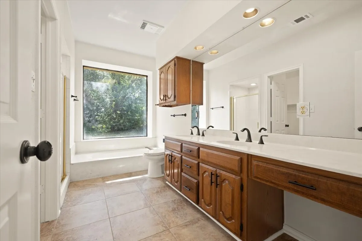 Expansive vanity with dual sinks, warm wood cabinetry, and a full-width mirror