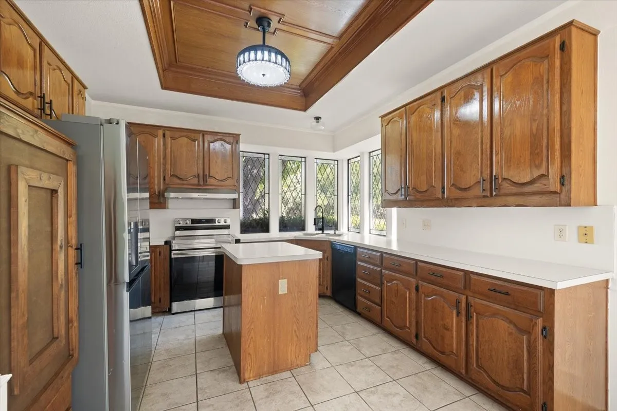 Kitchen featuring wood cabinetry, white countertops, a central island, and tiled flooring