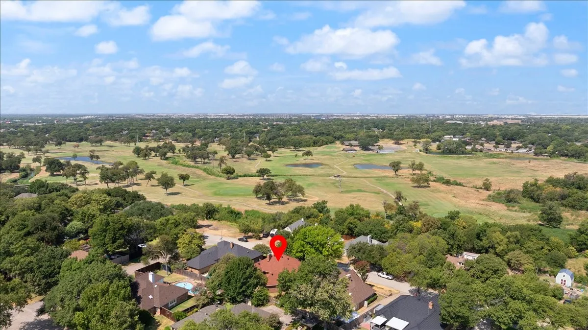 Aerial perspective showcasing the residential area surrounded by a golf course with mature trees and open green spaces