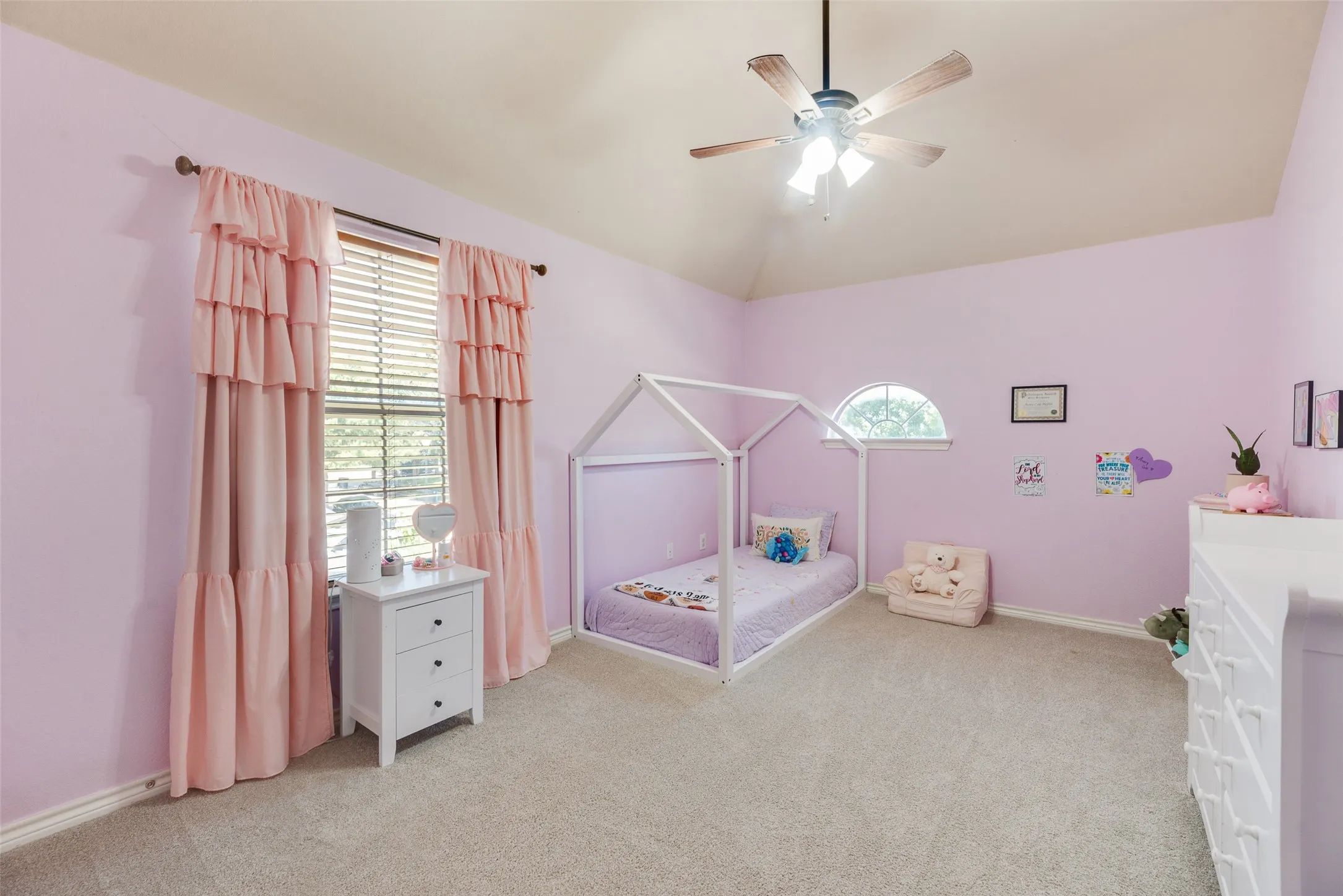 Vaulted ceiling with a ceiling fan, arched window, window with blinds, and light-colored carpet