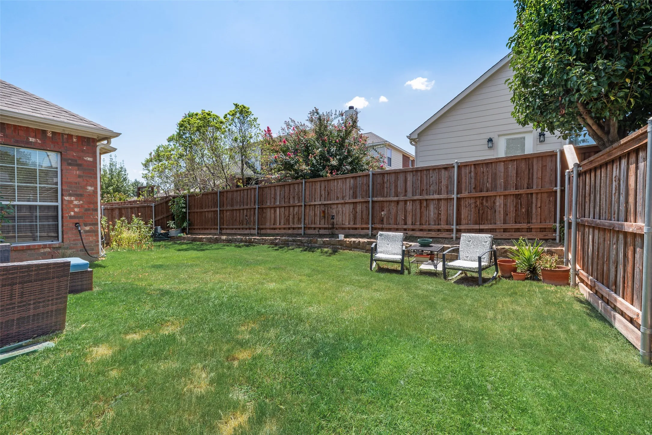 Expansive backyard featuring a wood privacy fence, brick exterior, and a large grassy area