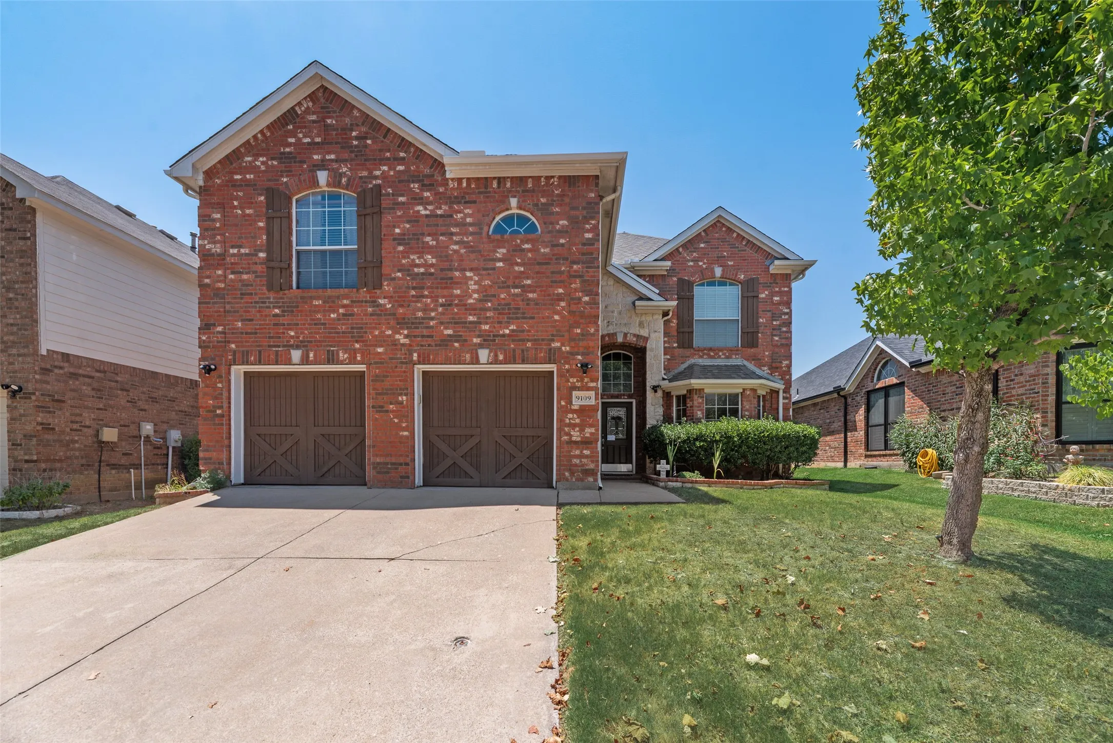 Brick exterior with arched windows, a two-car garage, and a concrete driveway
