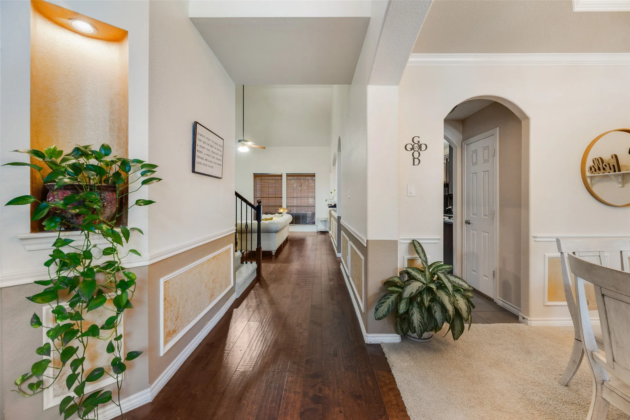 Hardwood-finish flooring, recessed wall niche with accent lighting, arched doorway, wainscoting, and crown molding