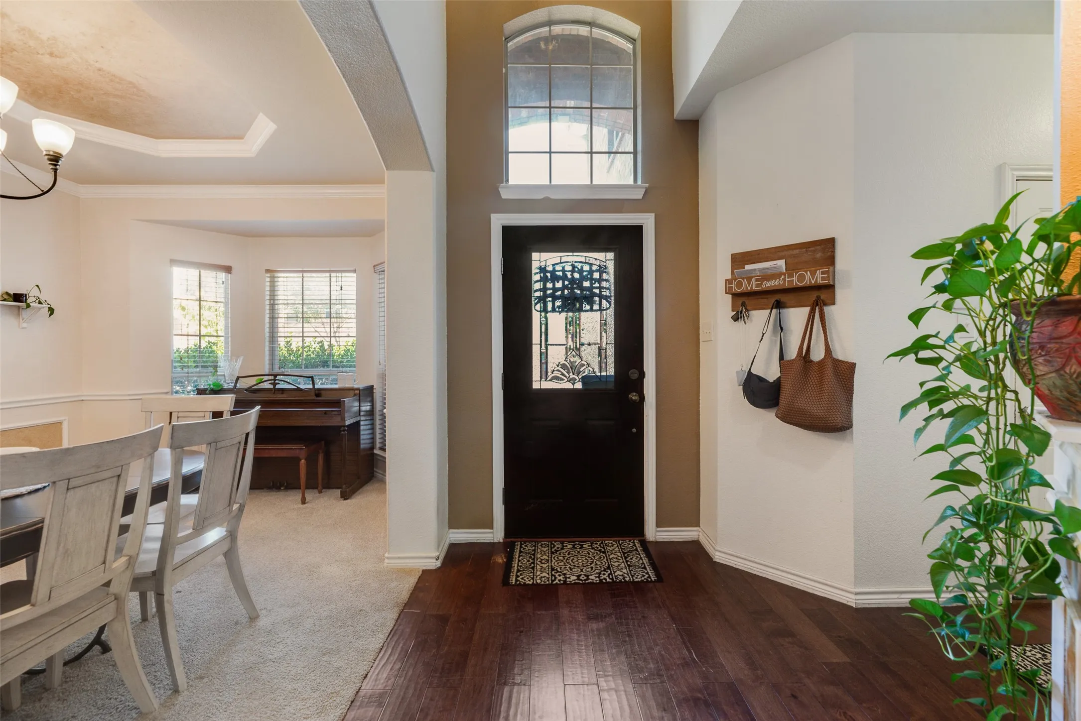 Entryway featuring wood-finish flooring, a dark-paneled door with decorative glass, and an arched transom window