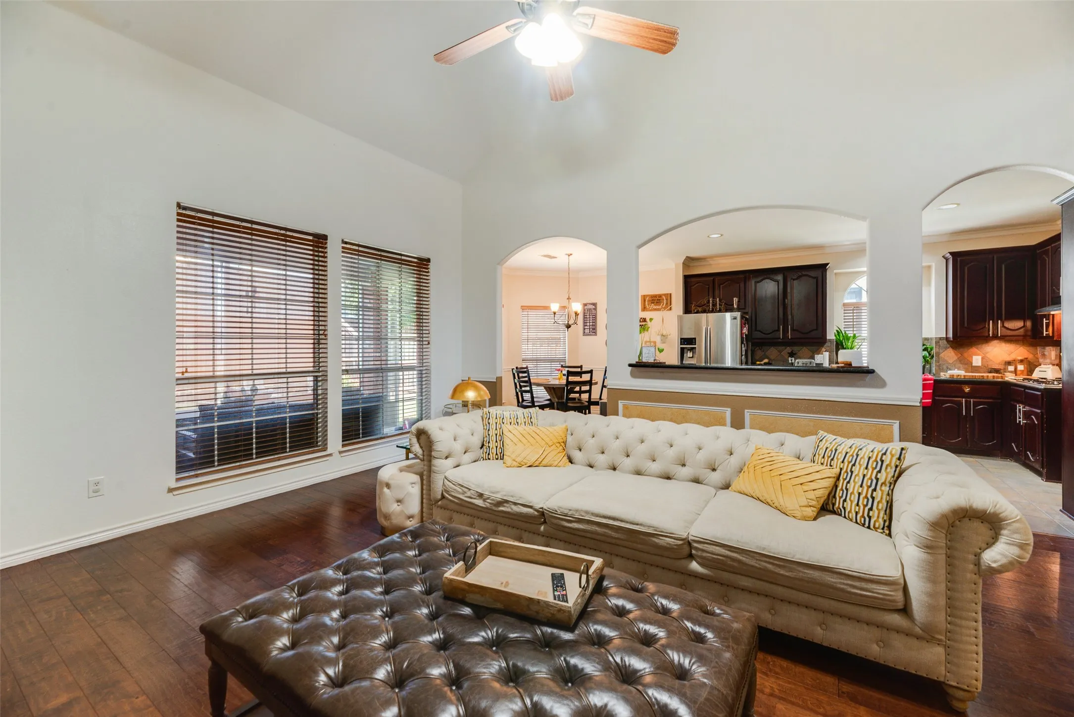 Wood-finish flooring with arched room entries, vaulted ceilings, and a ceiling fan with integrated lighting