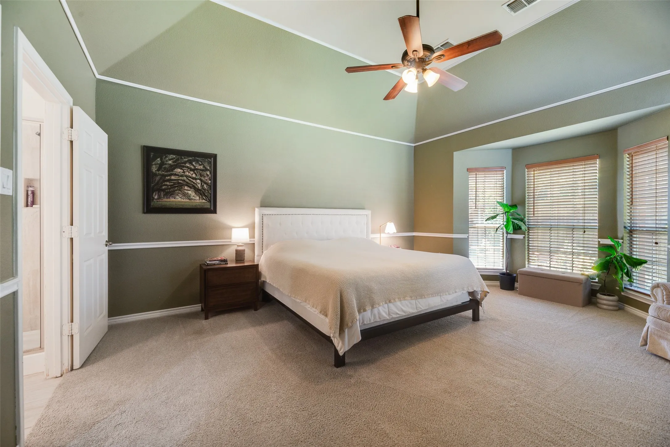 Vaulted ceiling with a ceiling fan, bay windows with blinds, built-in shelving, and carpet flooring