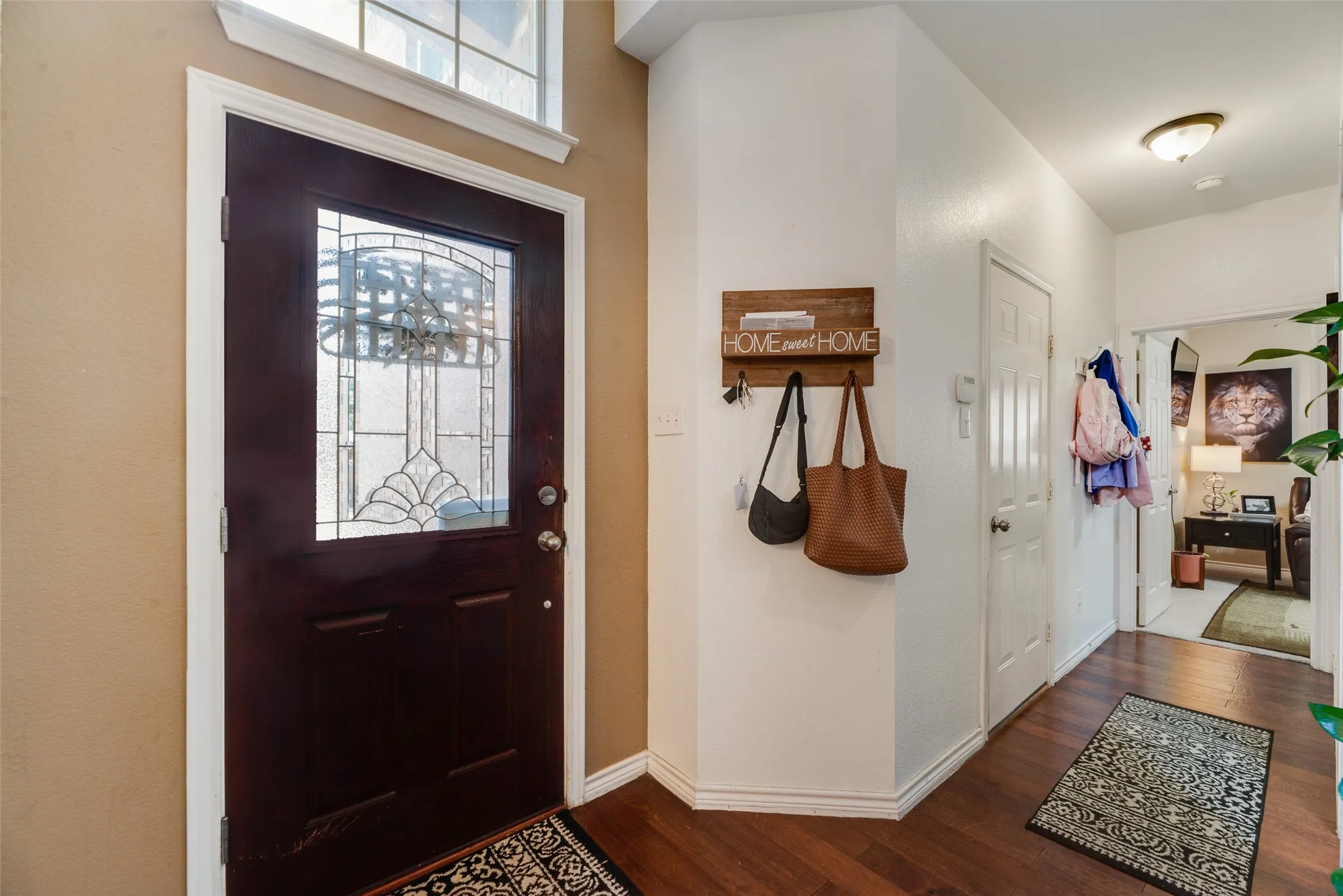 Dark wood-finish entry door with decorative glass inlay and transom window