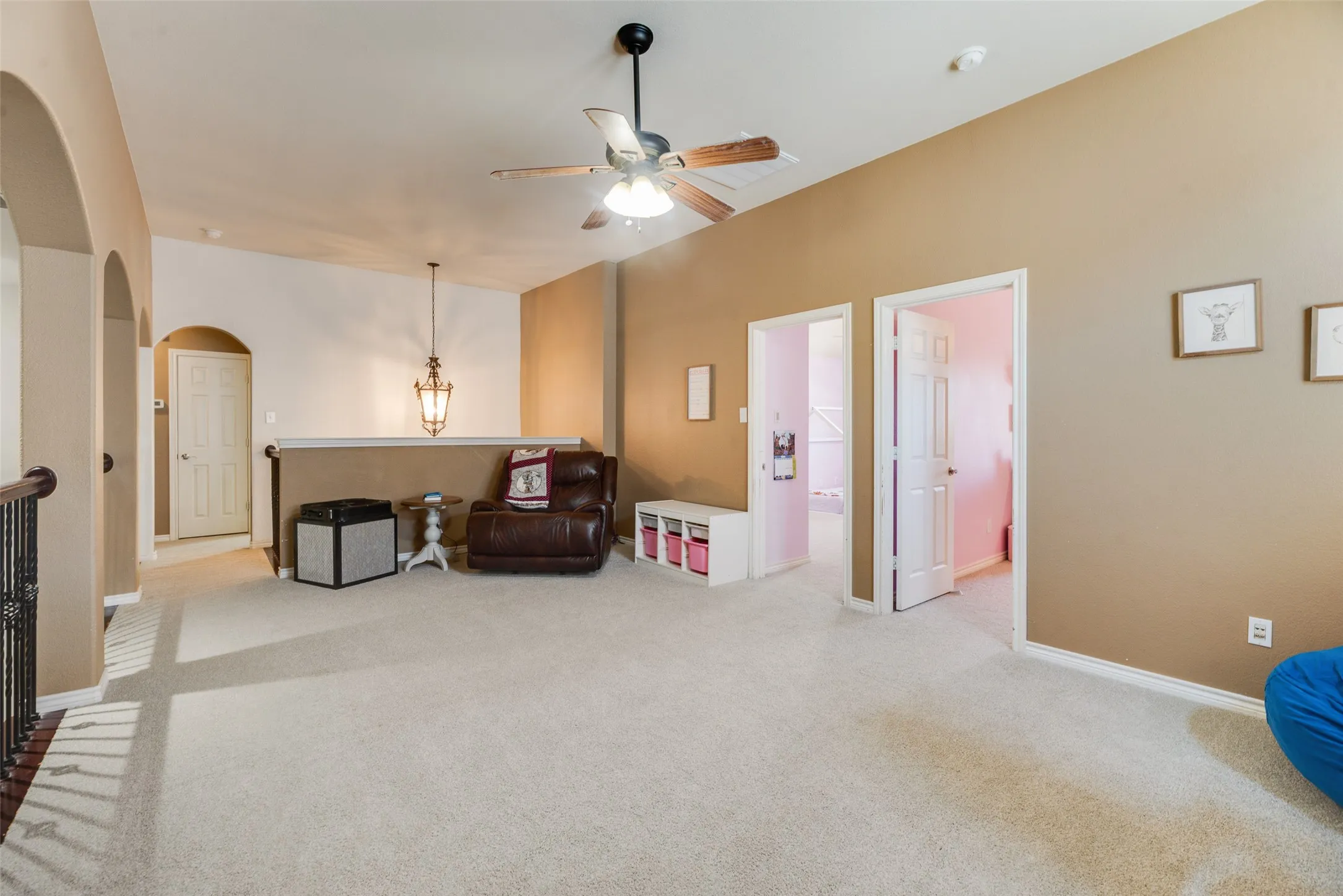 Vaulted ceiling with a ceiling fan, carpeted flooring, arched doorways, and a suspended lantern fixture