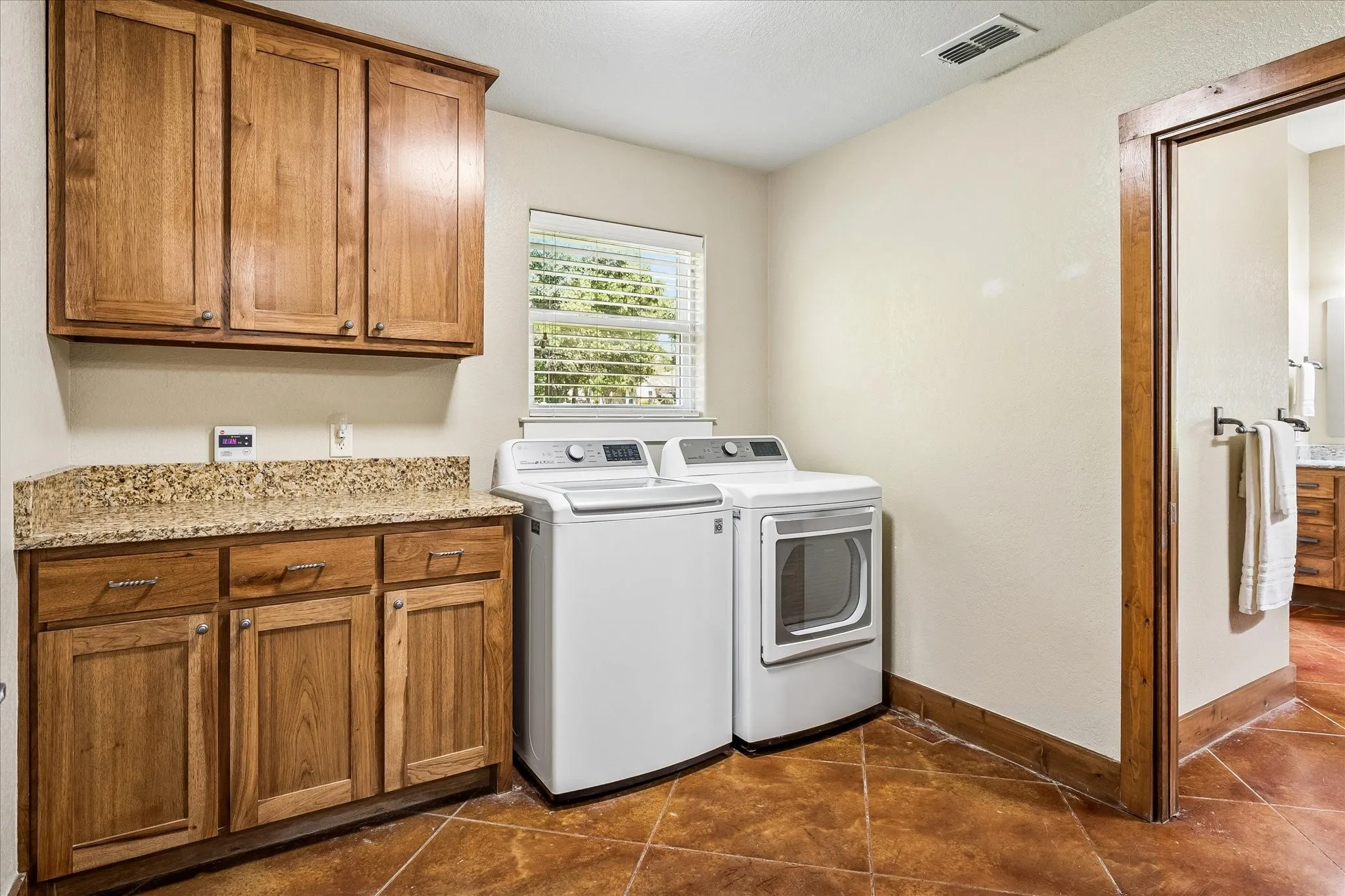 Laundry area with wood cabinetry, light-toned walls, and a window