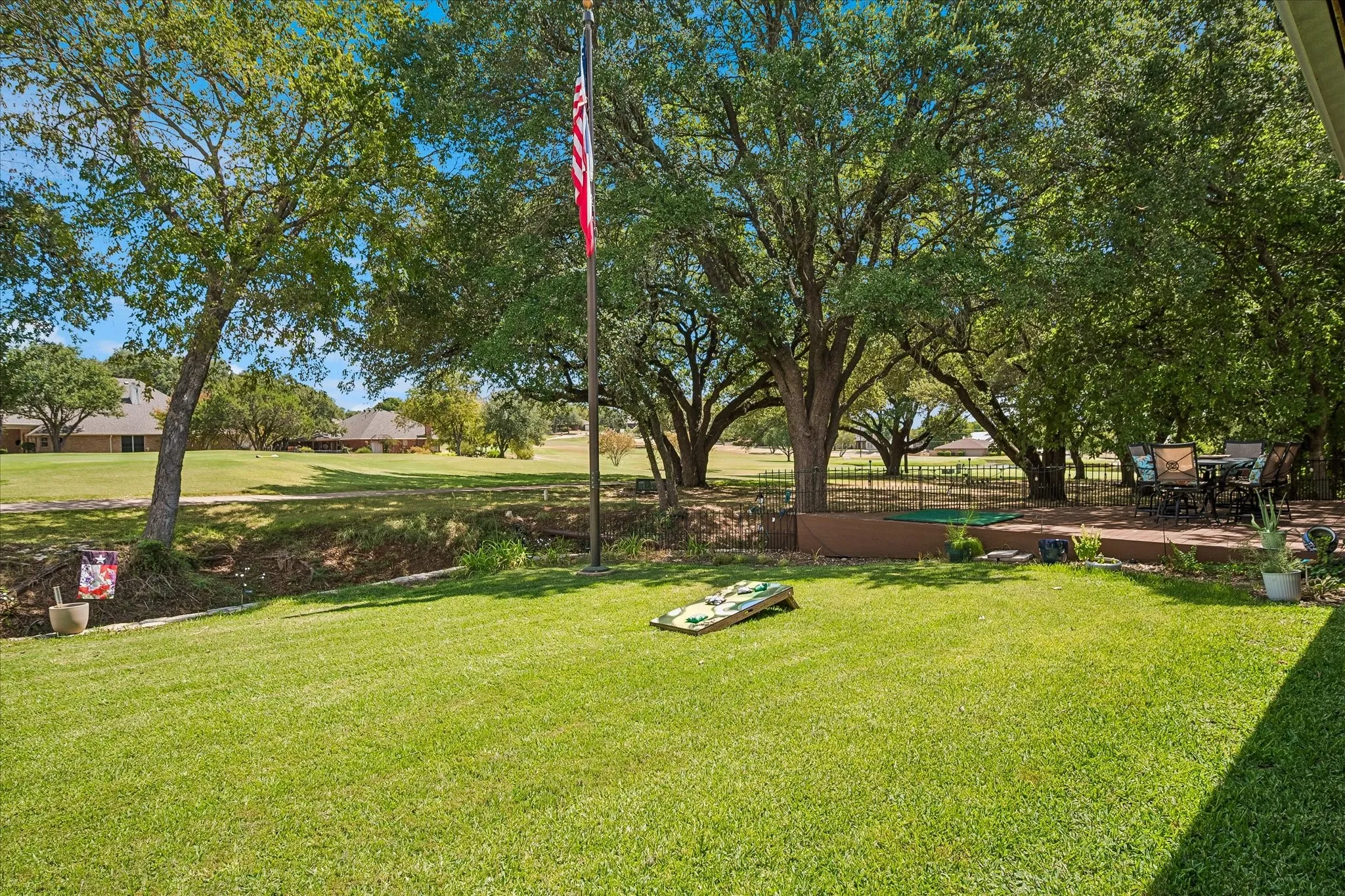 Expansive lawn with mature trees and a concrete and trex type  patio one open and one covered