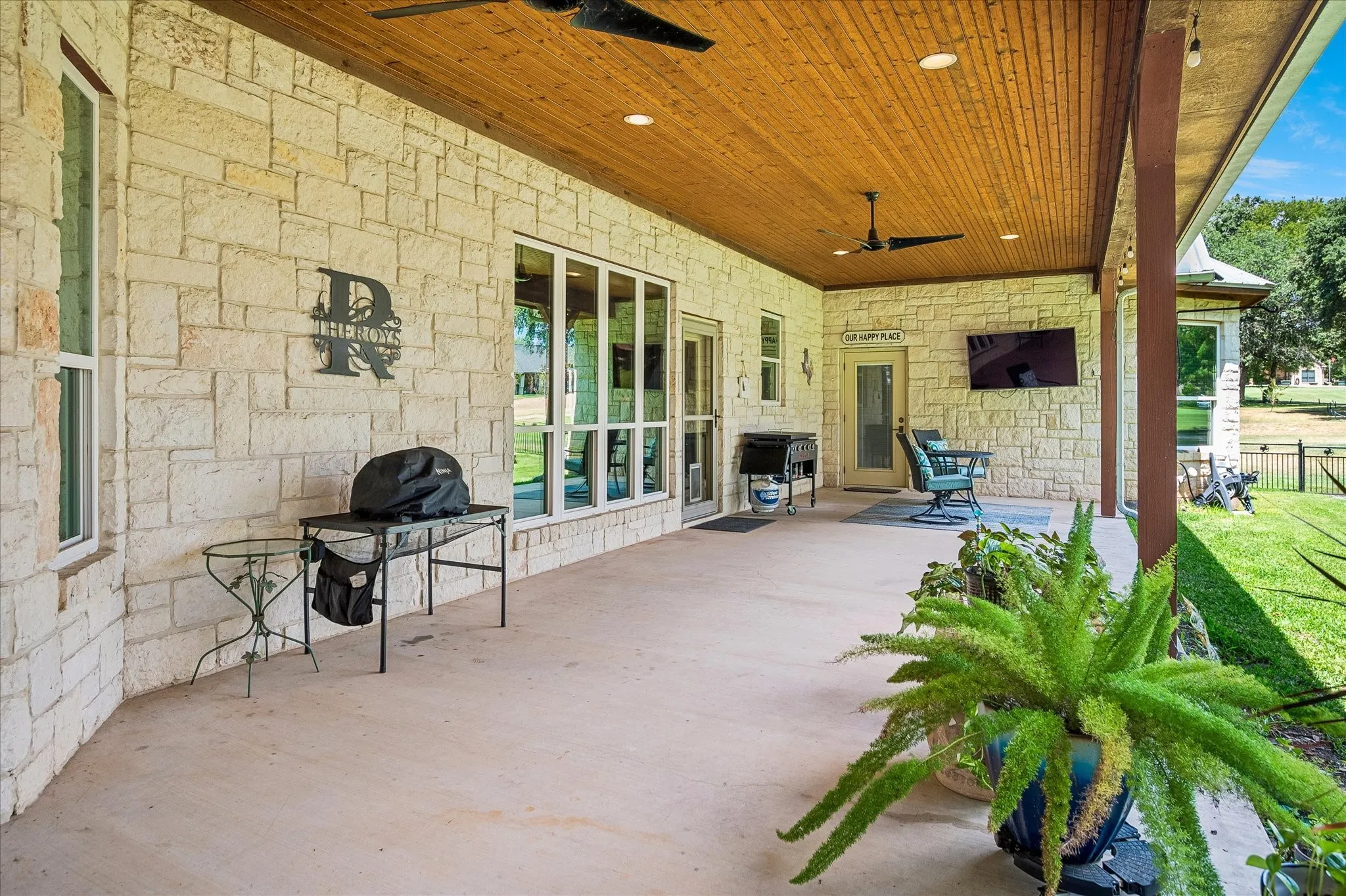 Expansive covered patio featuring a wood-finish ceiling, stone exterior wall, recessed lighting, and ceiling fans