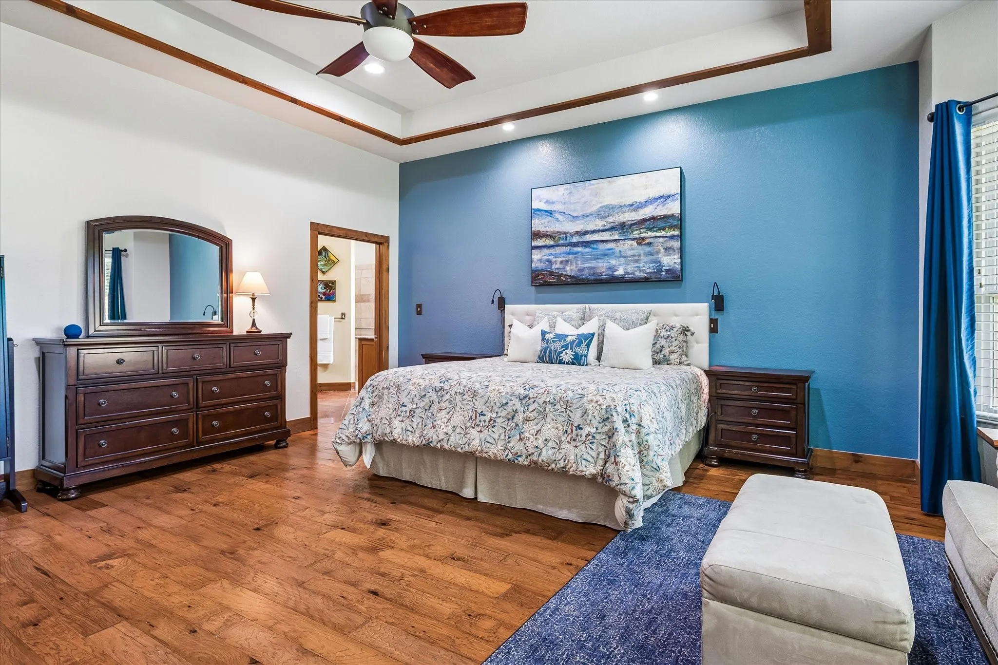Tray ceiling with wood-finish trim, recessed lighting, and a ceiling fan