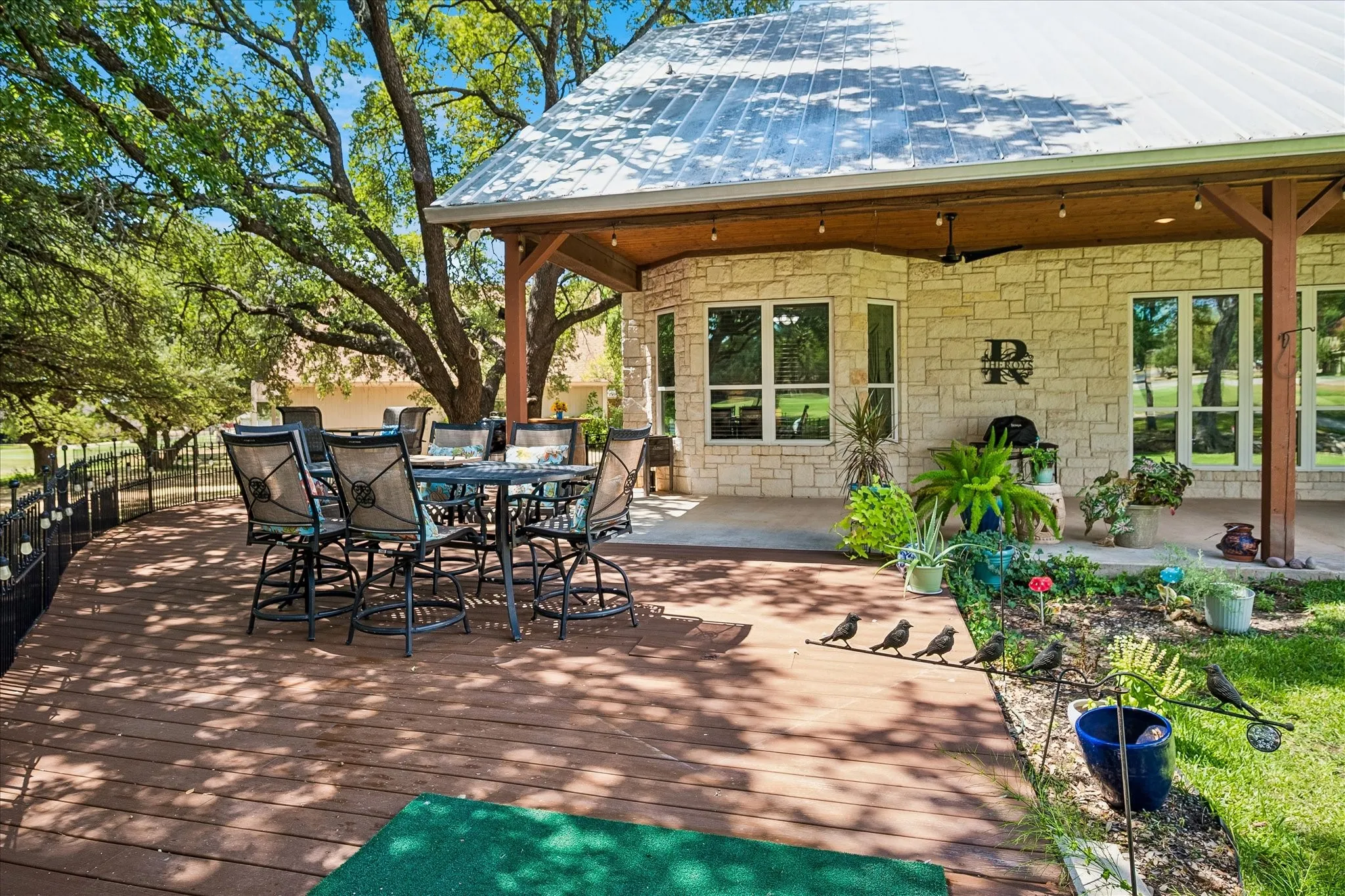 Expansive outdoor deck with a metal roof overhang, stone exterior, and built-in lighting