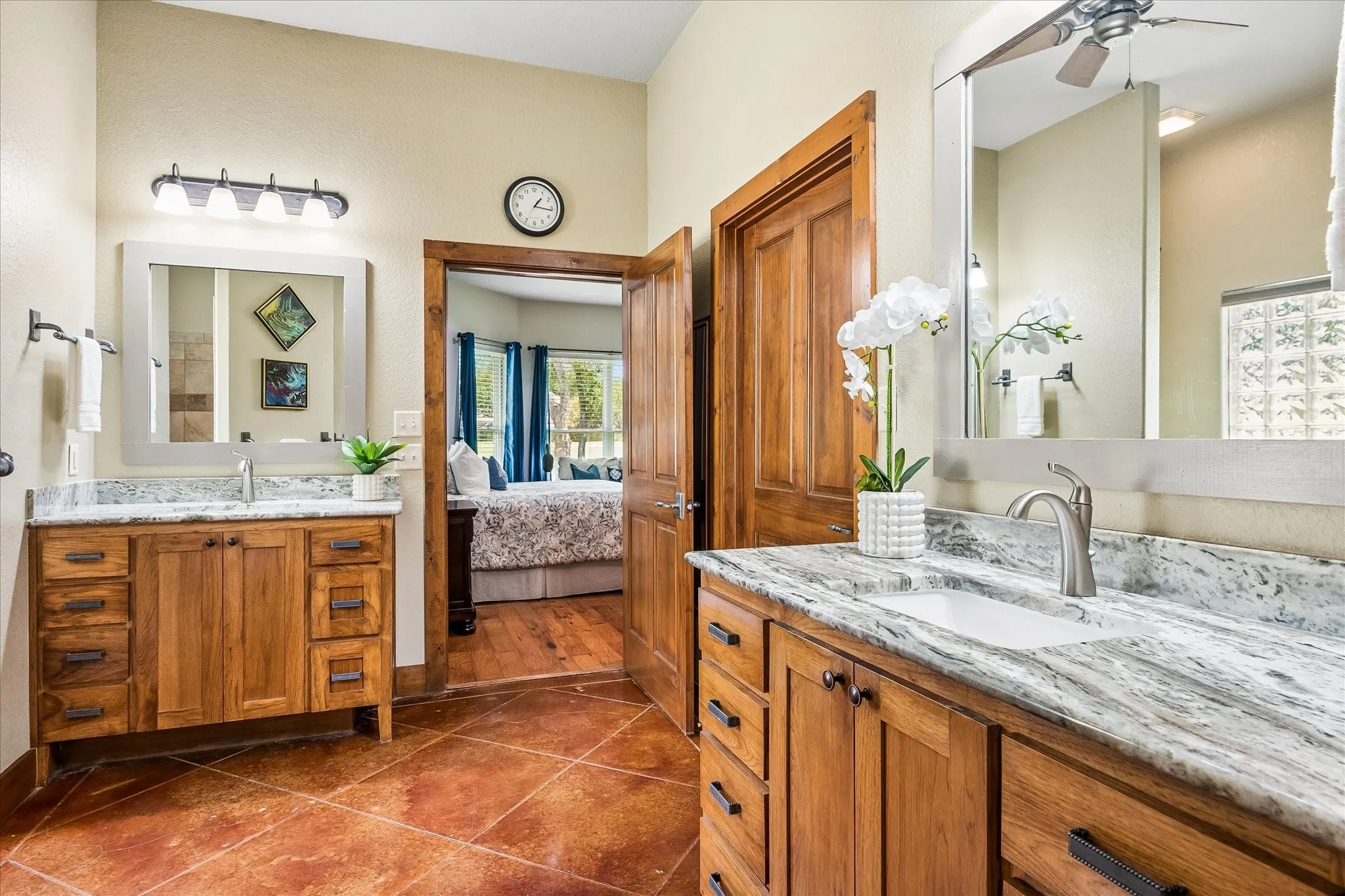 Dual wood-finish vanities with undermount sinks, stone countertops, and framed mirrors