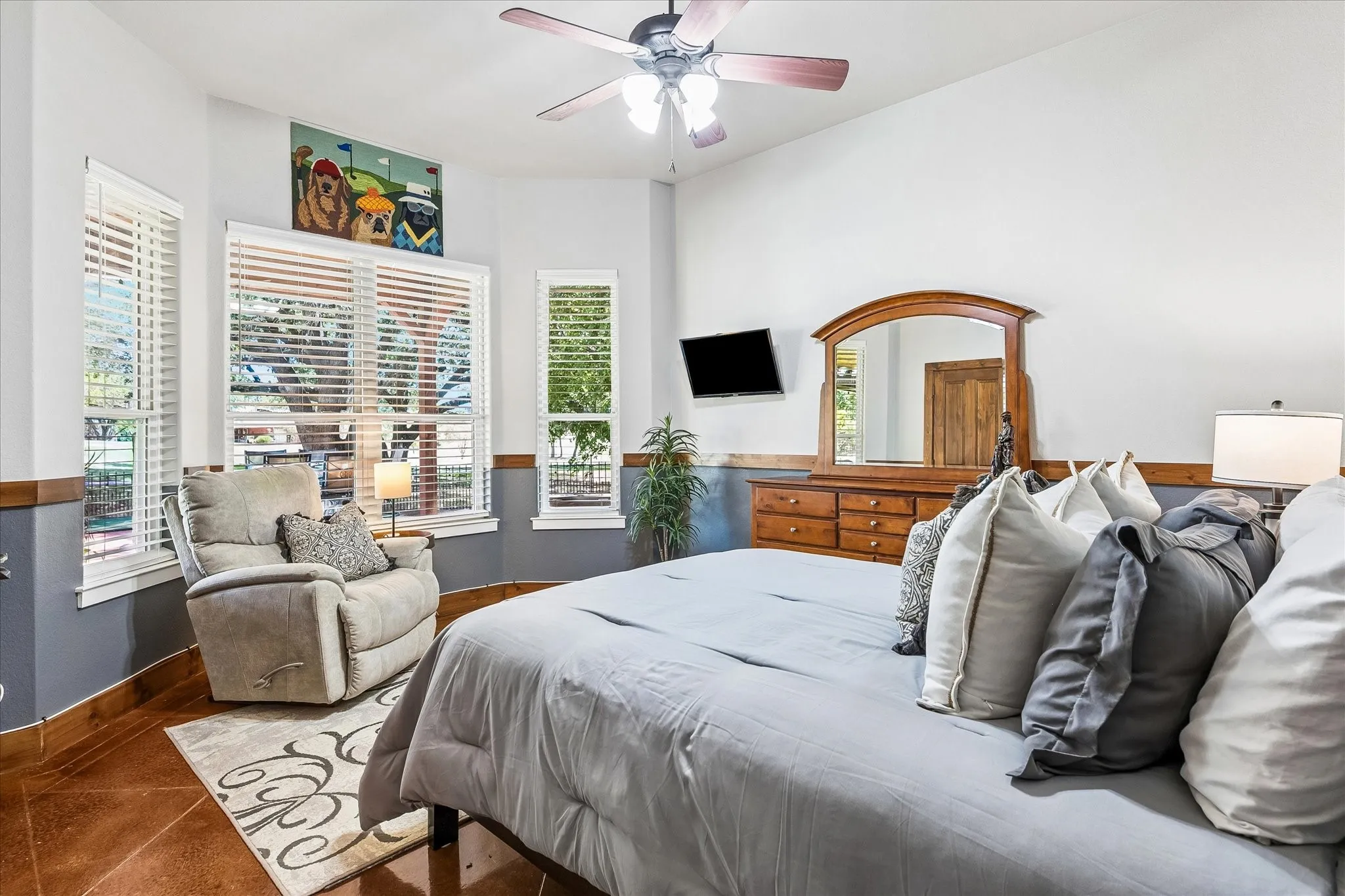 Vaulted ceiling with a ceiling fan, multiple windows with blinds, two-tone wall treatment, and durable flooring