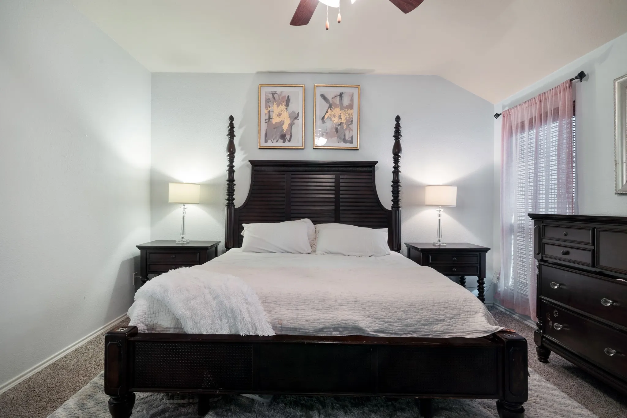 Angled ceiling, window with curtain rod, ceiling fan, and carpeted flooring