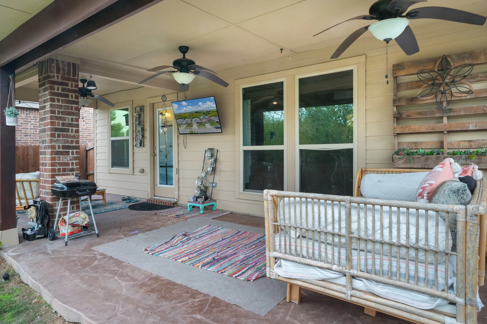 Covered patio featuring a stamped concrete surface, brick support column, and dual ceiling fans