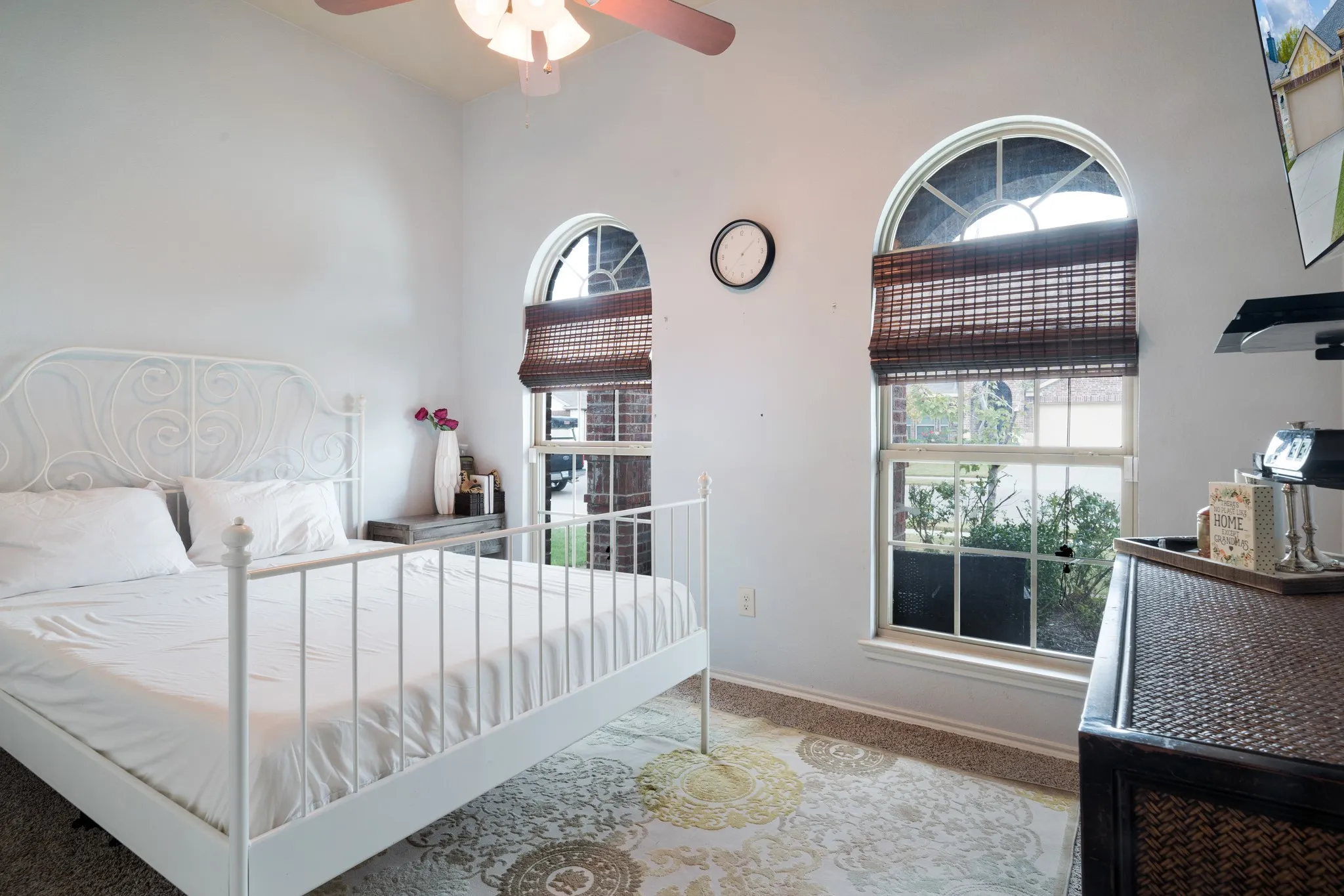 Vaulted ceiling with a ceiling fan, two arched top windows, and carpeted flooring