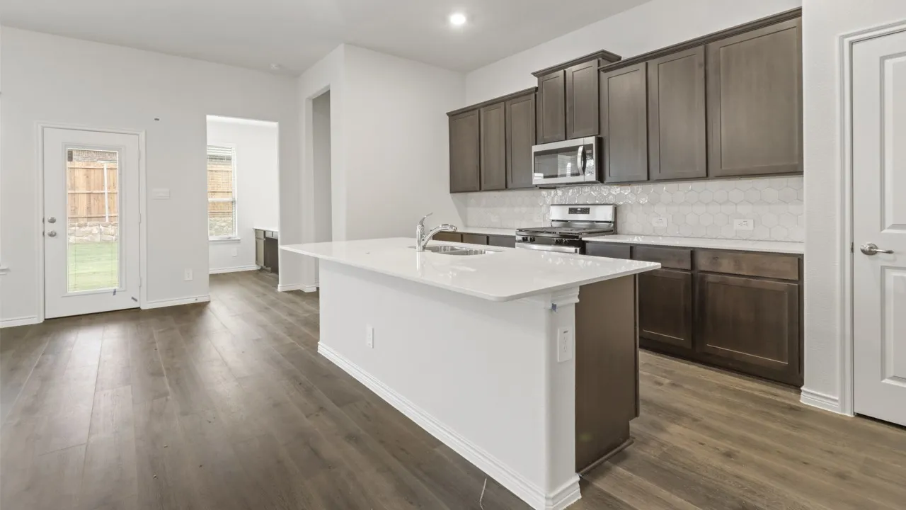Kitchen featuring a center island with sink, white countertops, dark wood cabinetry, stainless steel appliances, and wood-finish flooring