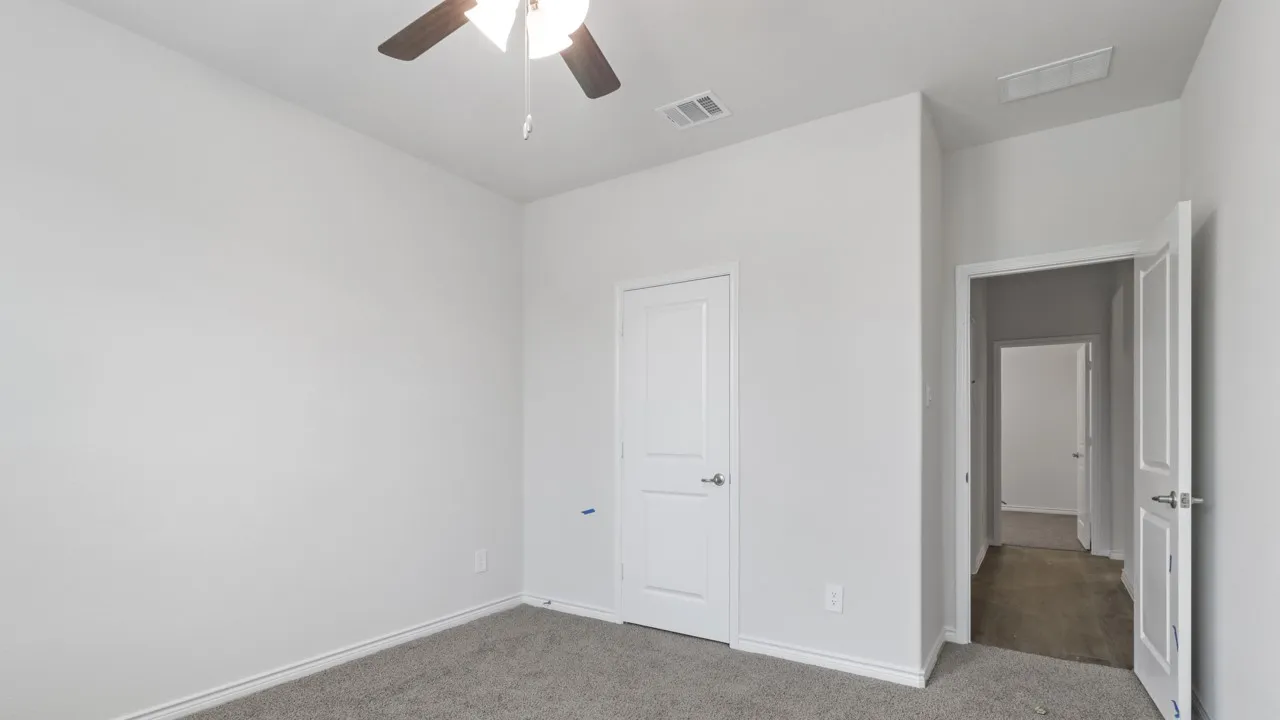 Ceiling fan with integrated lighting, neutral wall finishes, and gray carpet