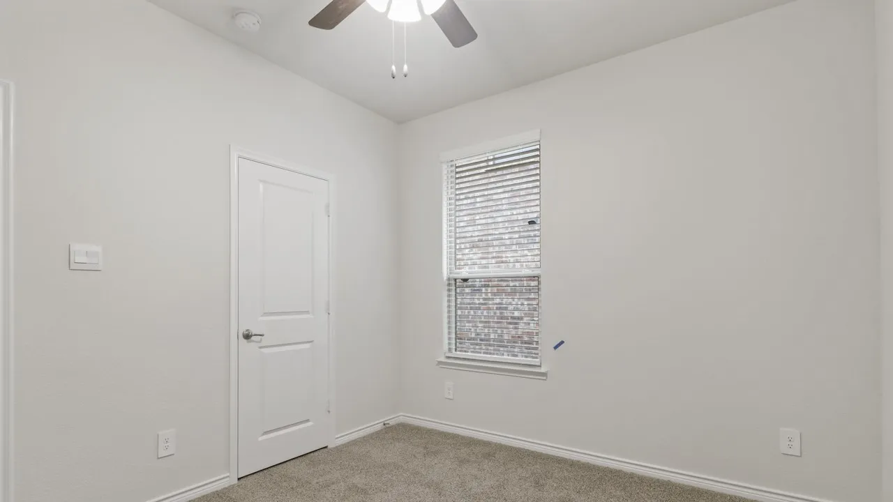 Recessed window with blinds, overhead ceiling fan with light fixture, light gray wall finish, and neutral carpet flooring