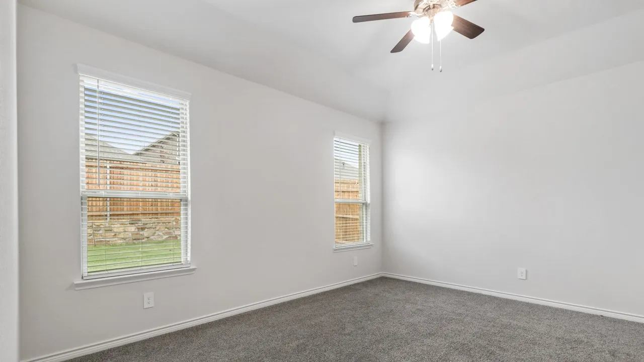 Spacious room with plush gray carpeting, white painted walls, and two windows