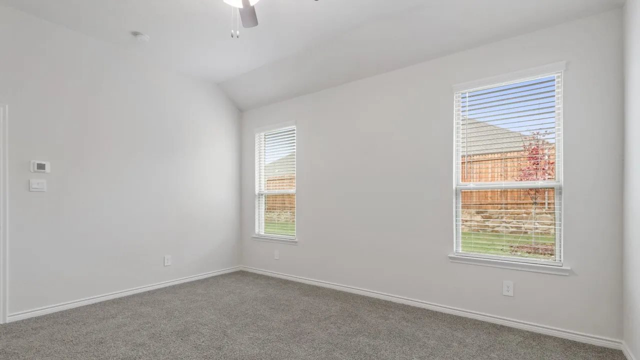 Vaulted ceiling with a ceiling fan, two windows with blinds, and carpeting