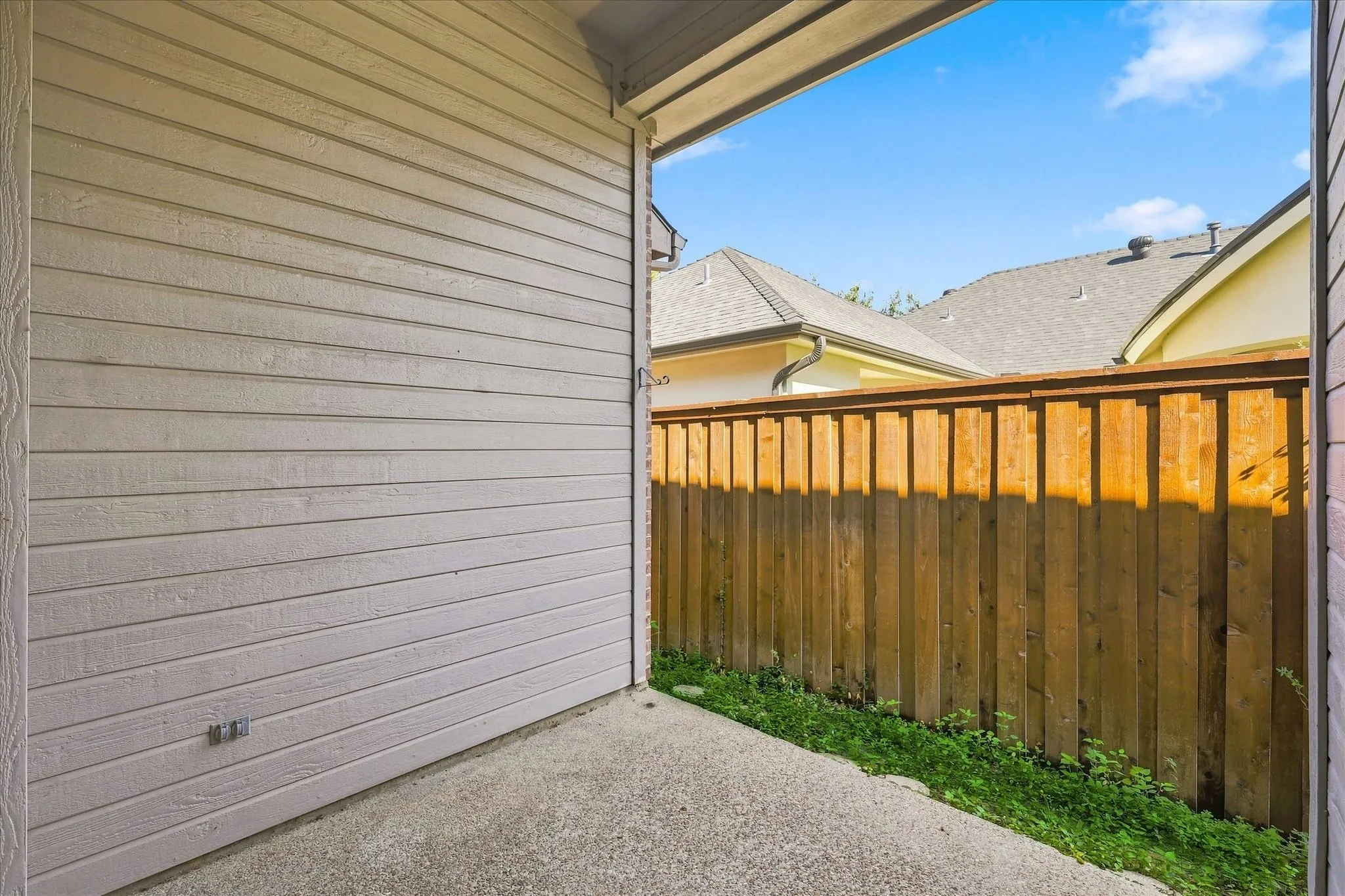 Covered patio with concrete flooring, wood fence, and horizontal siding