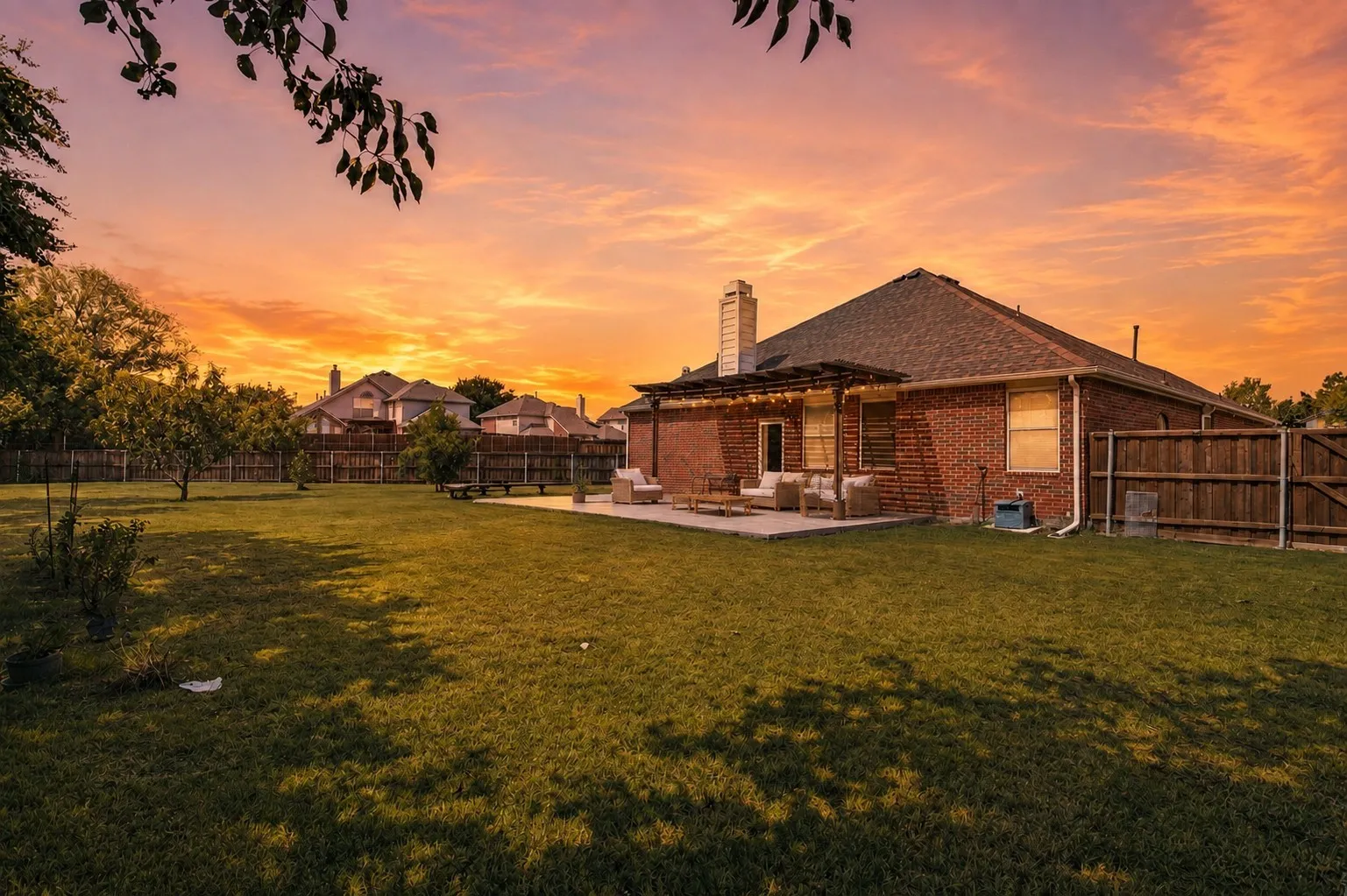 Expansive backyard featuring a manicured lawn, mature trees, and a concrete patio with an attached pergola