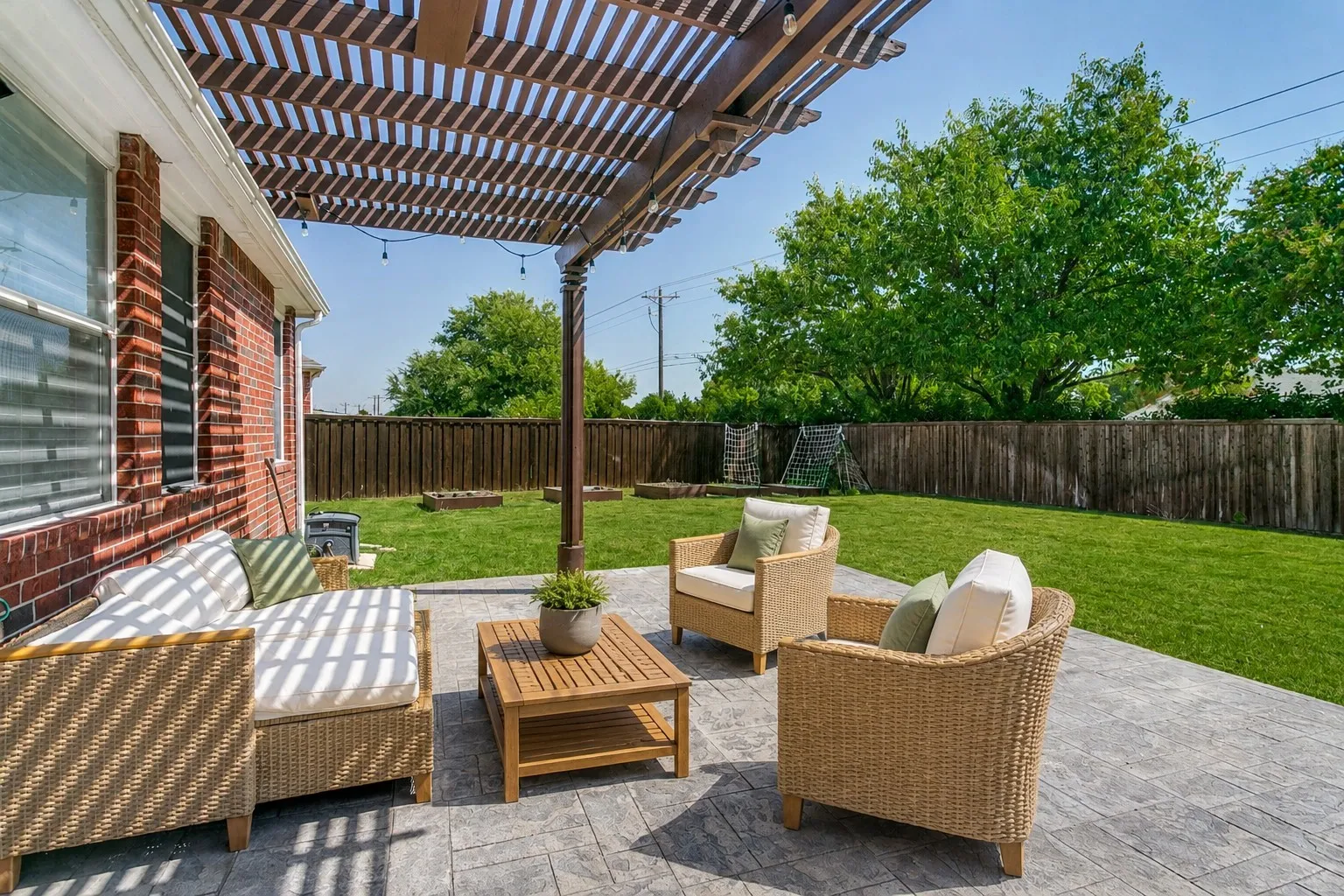 Outdoor patio with a slatted pergola, string lighting, and stamped concrete flooring