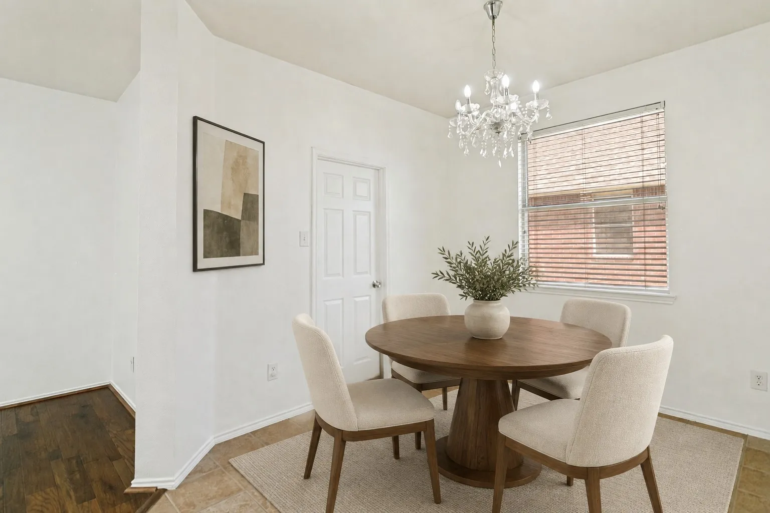 Recessed dining area with a multi-pane window, crystal chandelier, and light-toned tile flooring