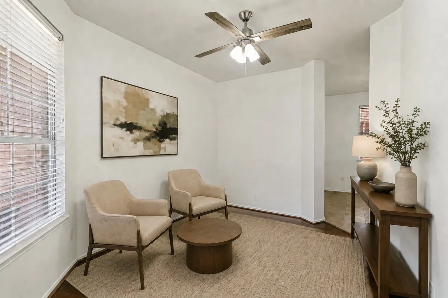 Hardwood flooring, white walls, and a ceiling fan with light fixture