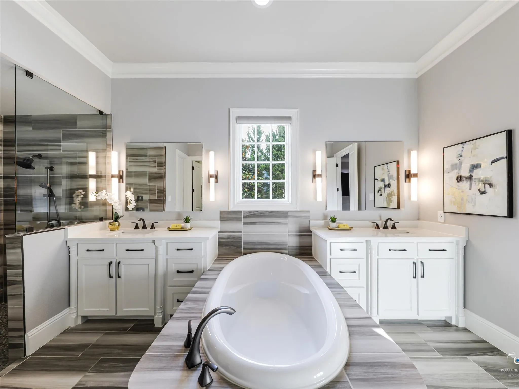 Primary bathroom with soaking tub, separate shower with custom tile, ceramic title, dual sink vanities and built in linen cabinet