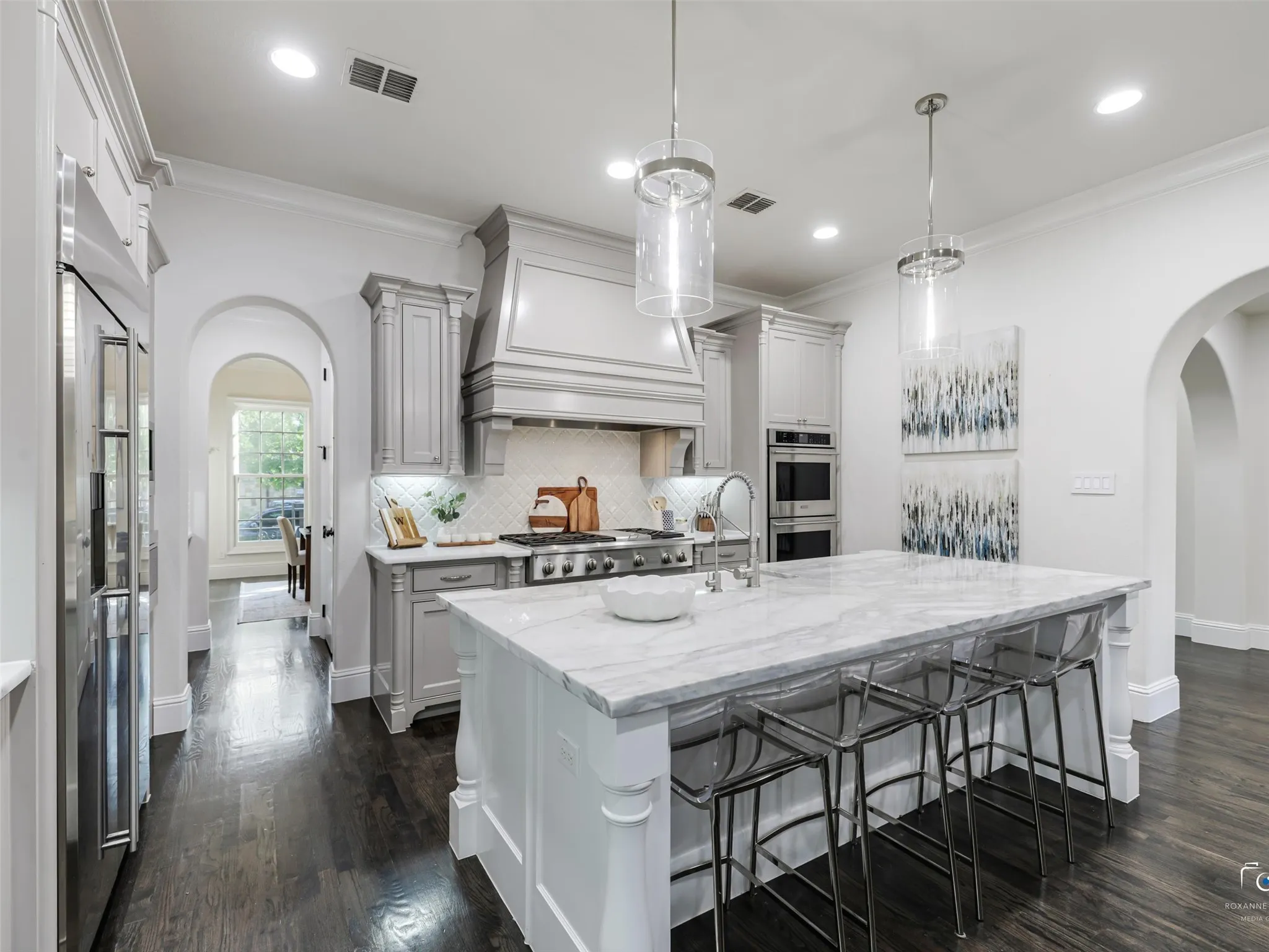 Kitchen with commercial grade gas cooktop, large island with breakfast bar, built-in refrigerator, double oven.