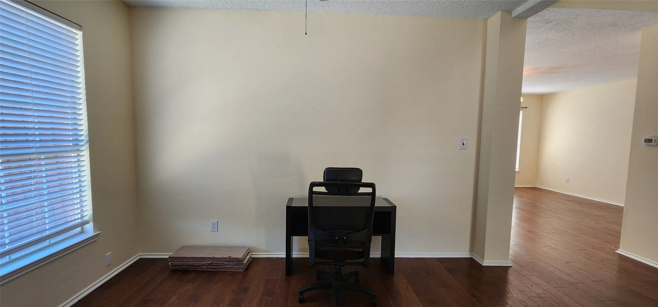 Wood-finish flooring throughout, light-toned walls, a window with horizontal blinds, and a wide entryway