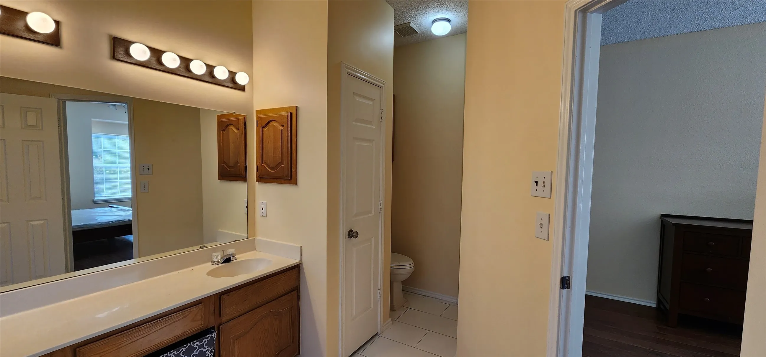 Extended vanity with integrated sink, wood-finish cabinetry, and overhead lighting