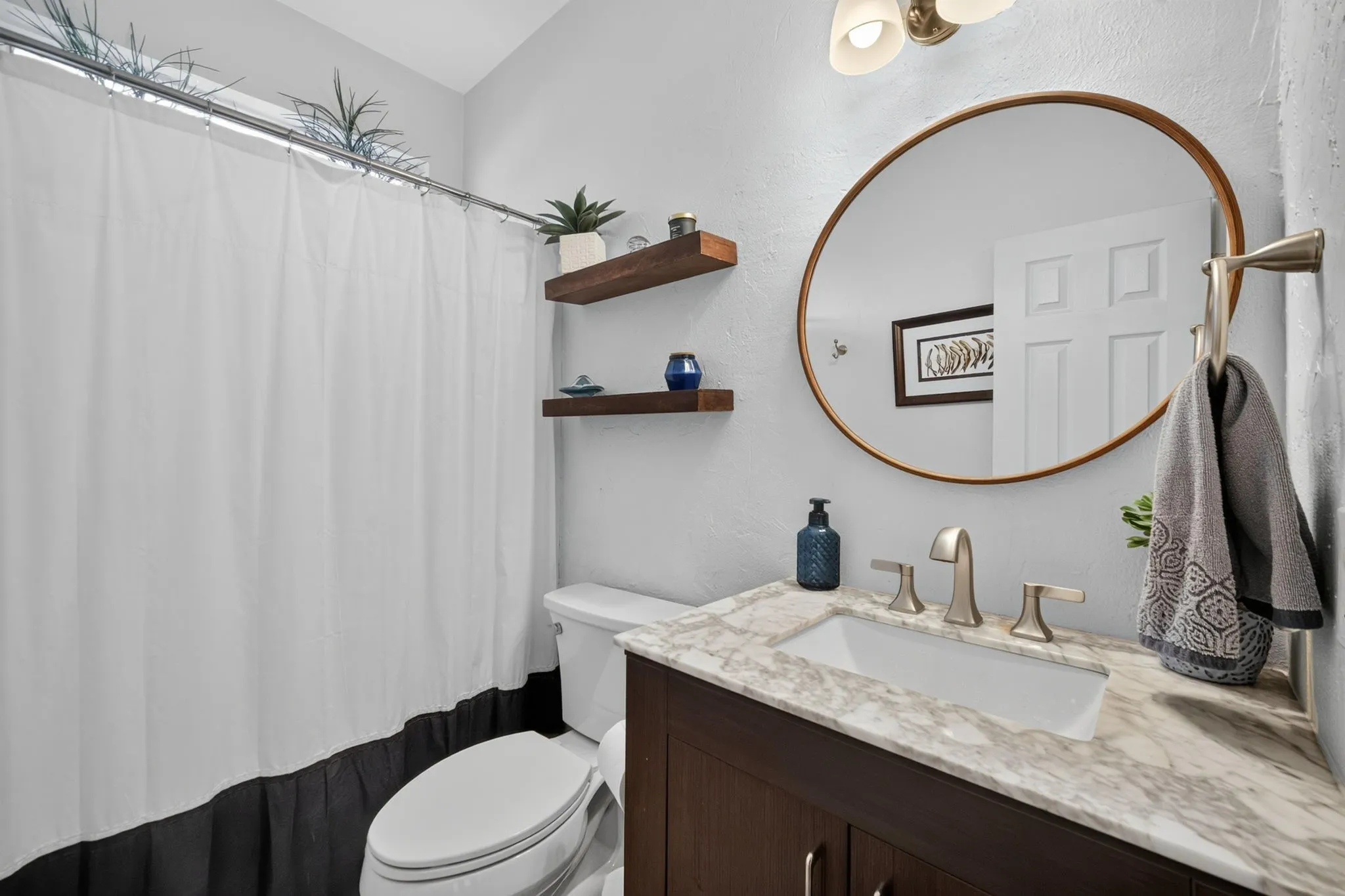 Dark wood-finish vanity with a light-toned countertop, oval-shaped mirror, and brushed nickel fixtures