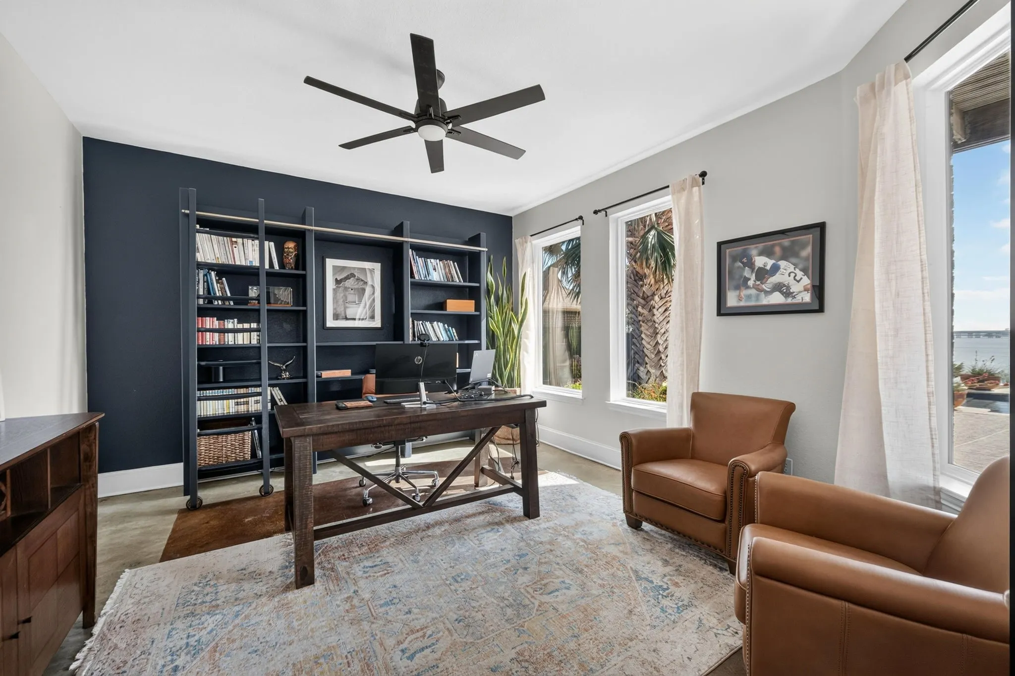 Multiple large windows providing lots of natural light, ceiling fan, and beautiful flooring