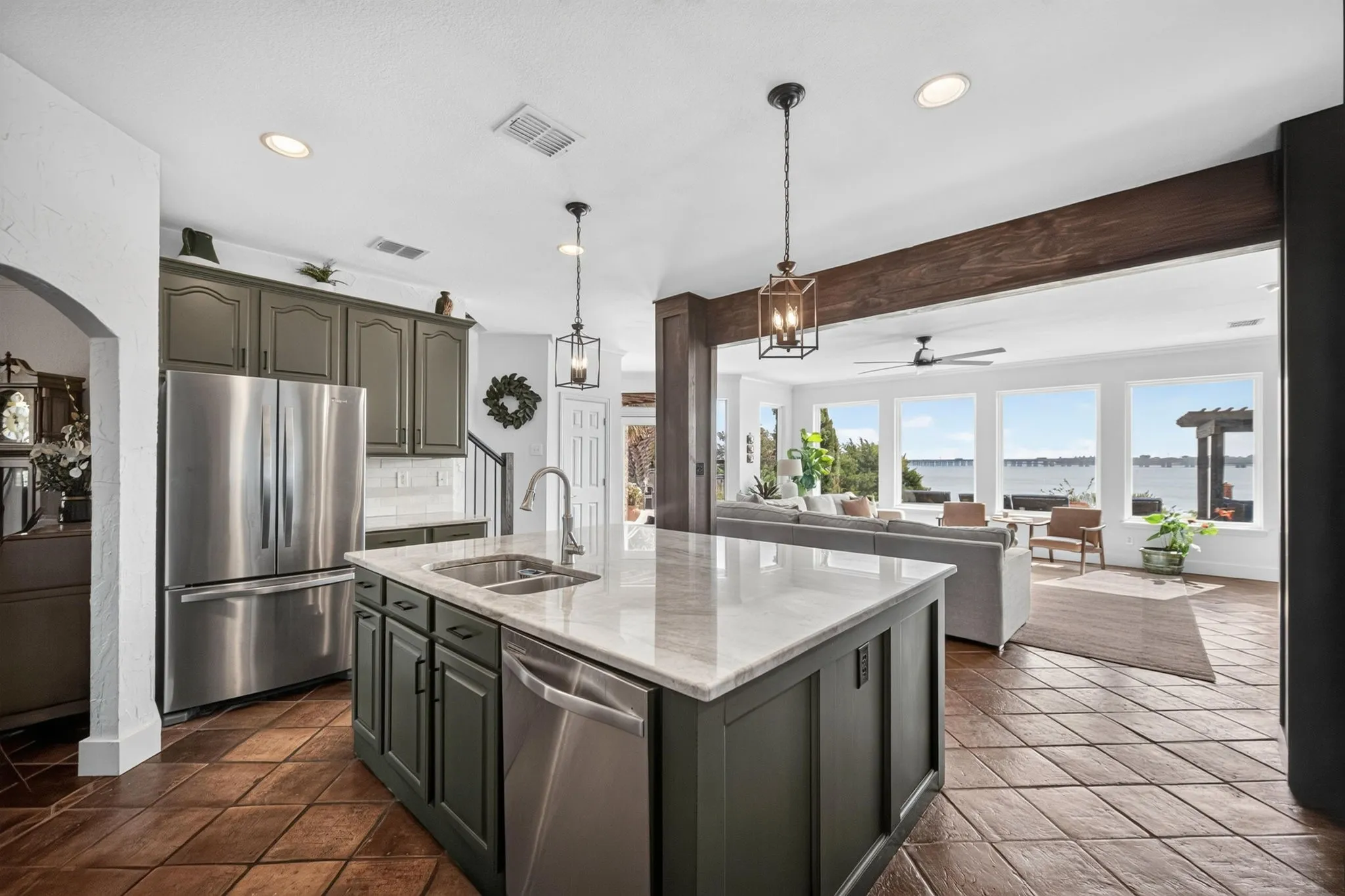 Kitchen island with integrated double basin sink, dark cabinetry, and white countertop